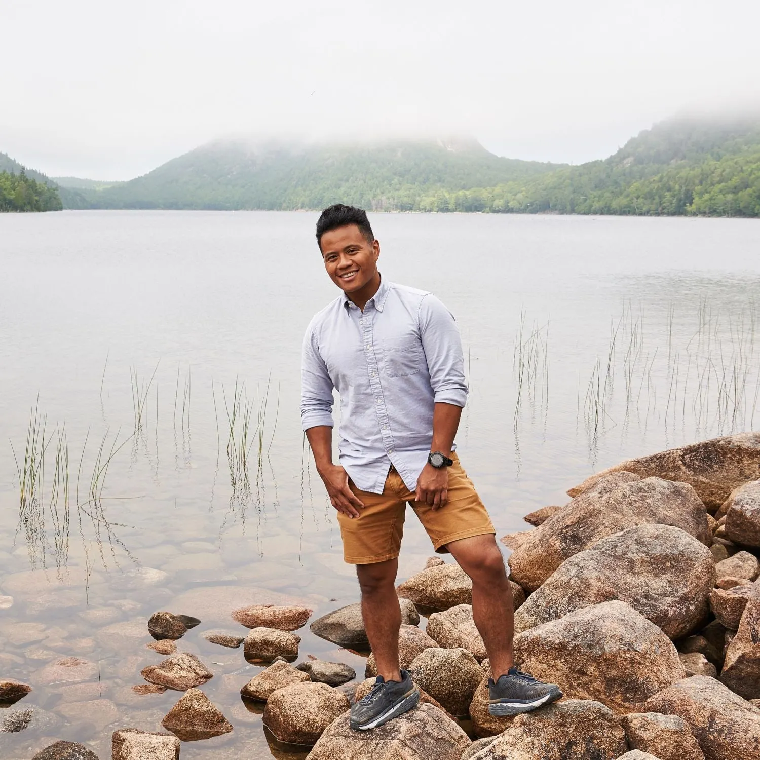 Angelito Jusay standing on the rocks at the edge of a misty mountain lake
