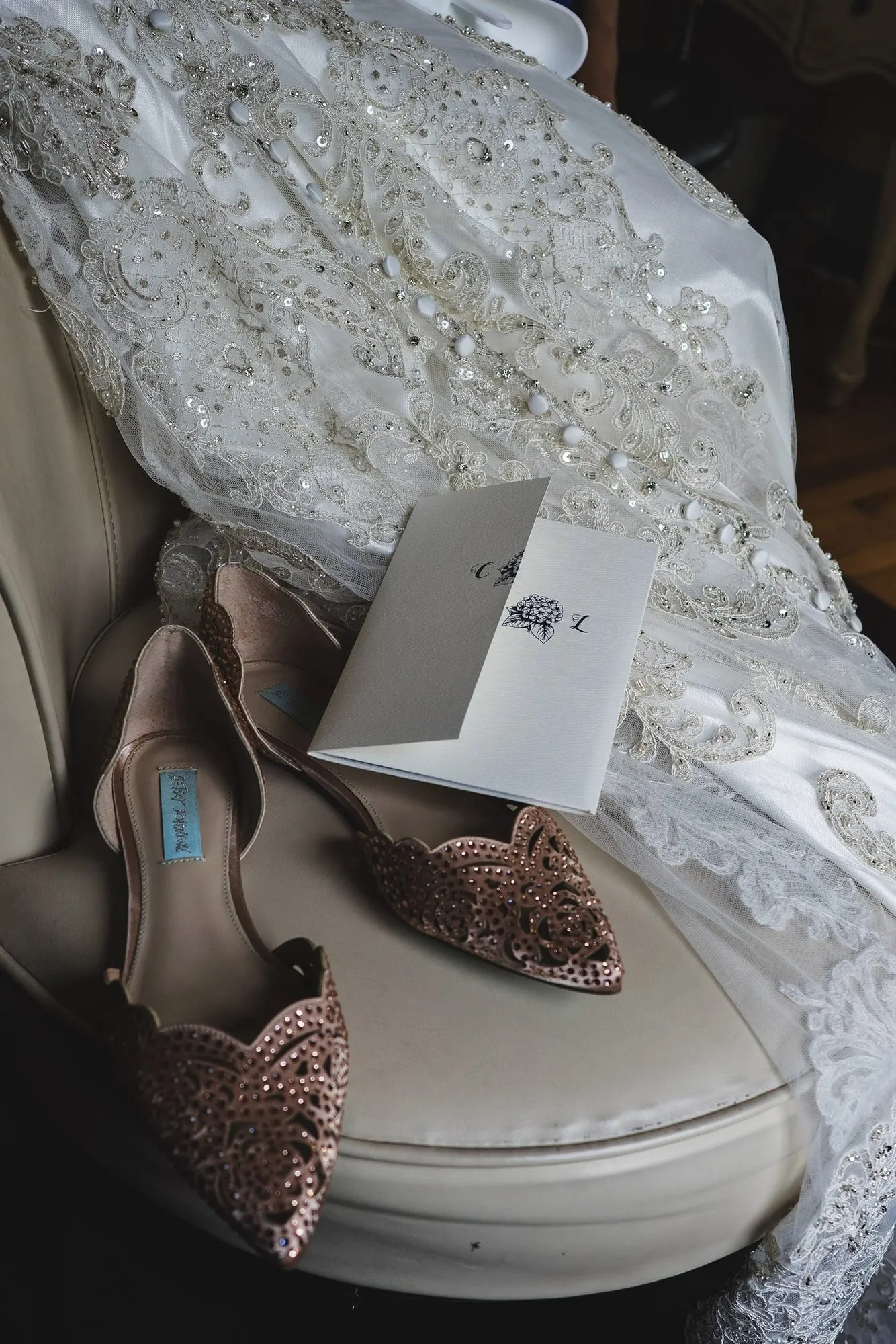 Bride's embellished heels and a note resting on her lace gown