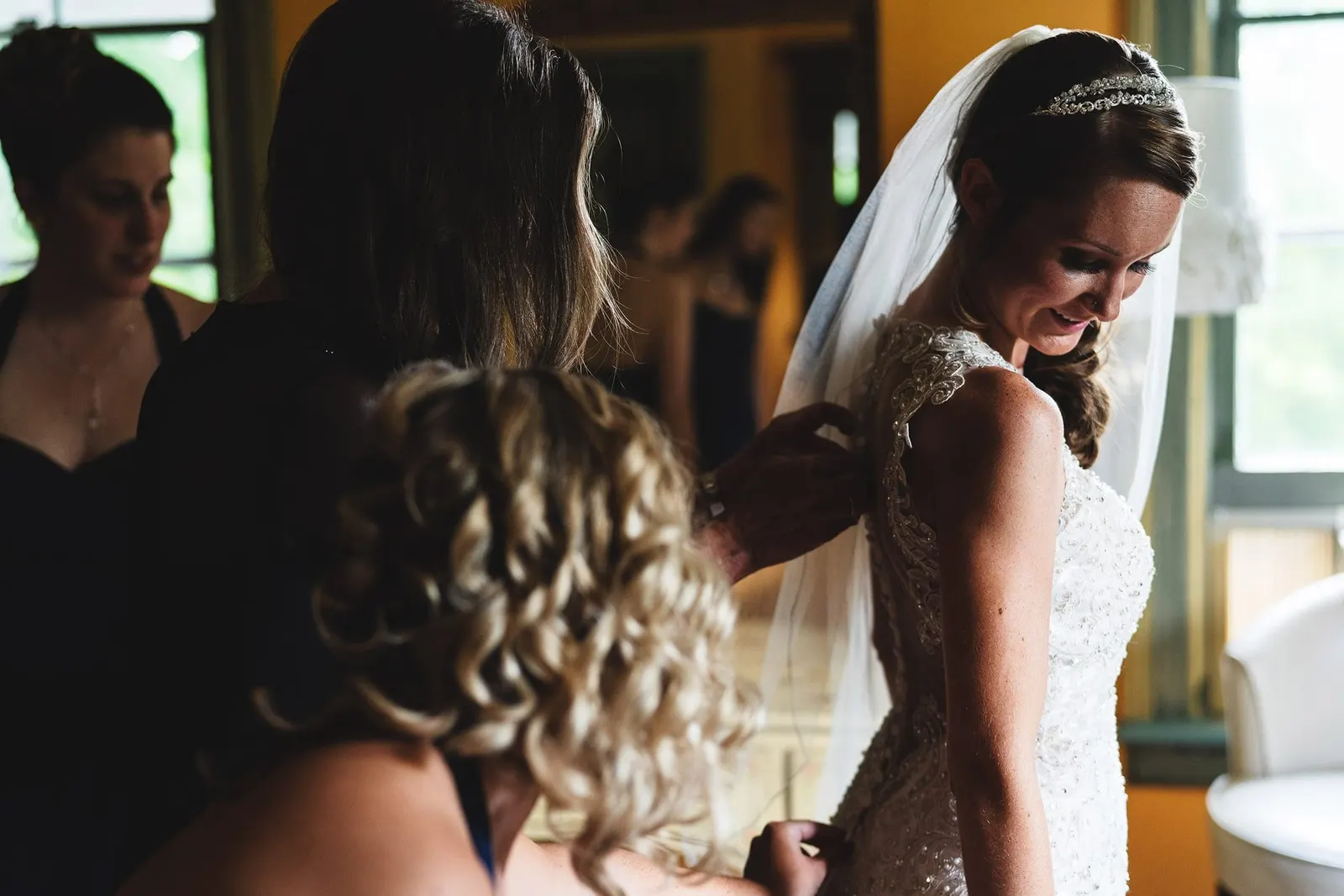 Bridesmaid adjusting the bride's veil while she gets ready