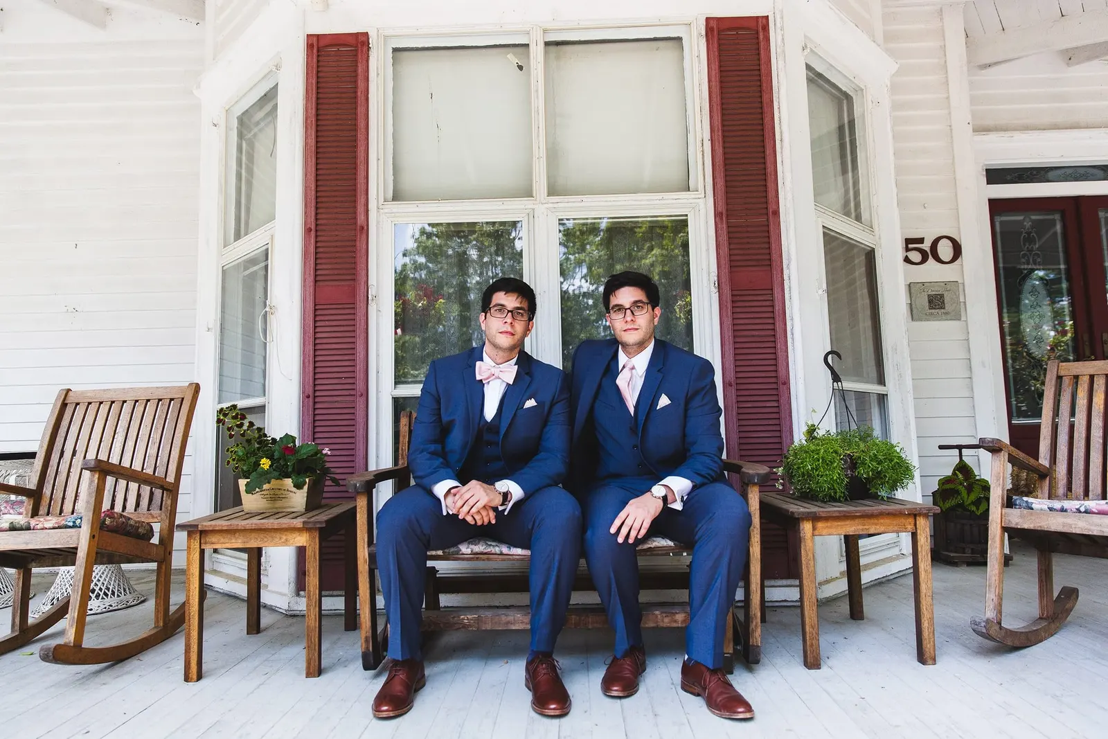 Groom and a groomsman seated on the farmhouse front porch