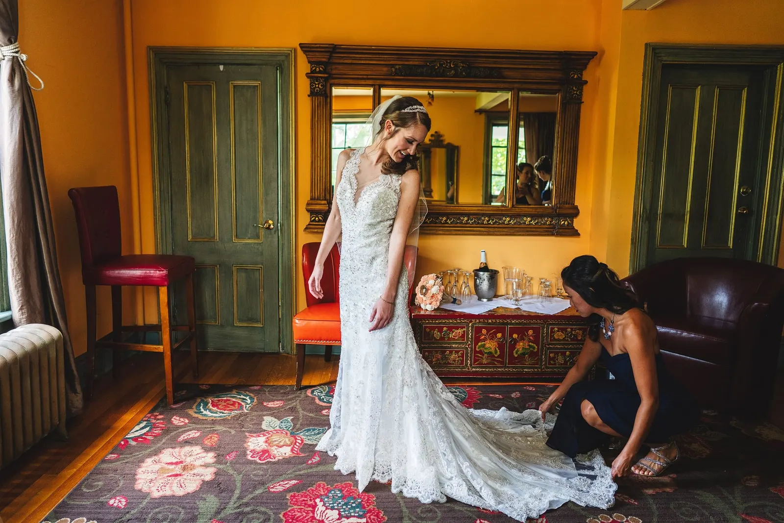 Bridesmaid arranging the bride's train in the farmhouse sitting room
