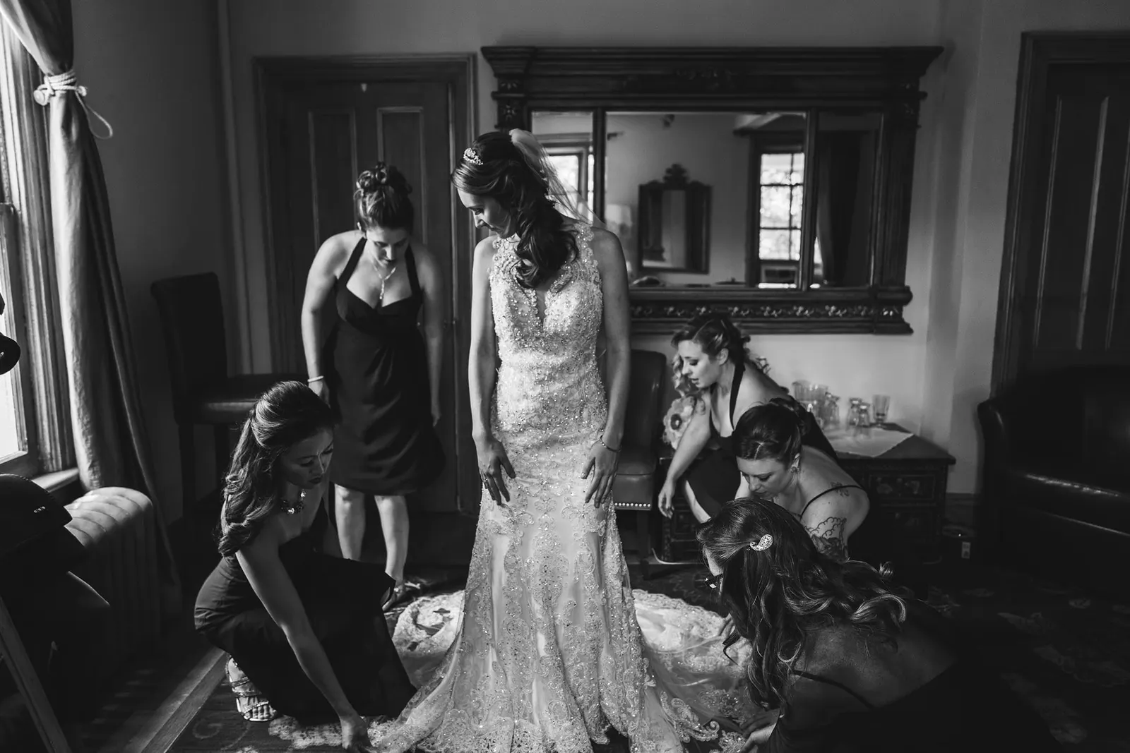 Black and white photo of bridesmaids helping the bride get ready