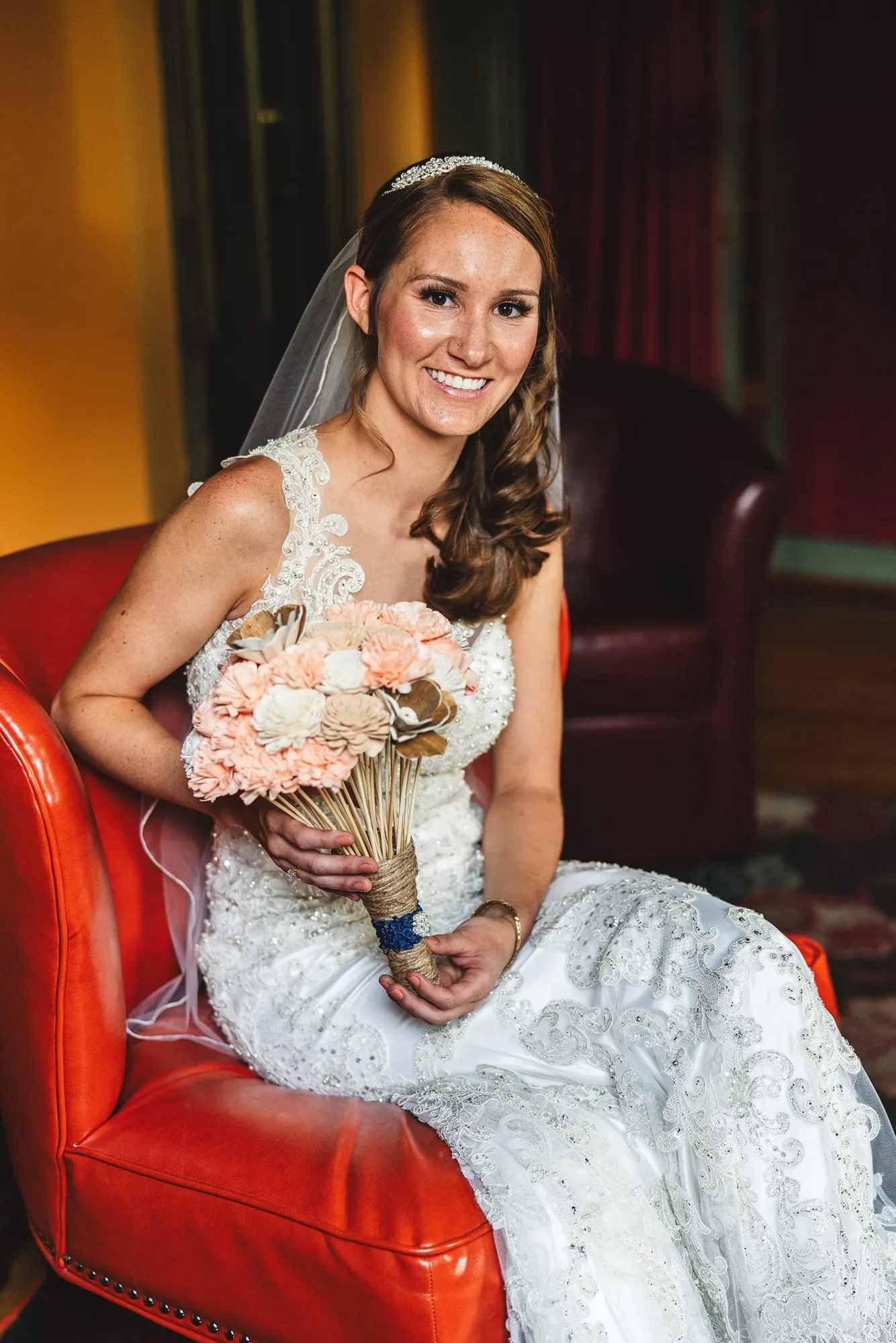 Bride holding her bouquet in a red leather armchair