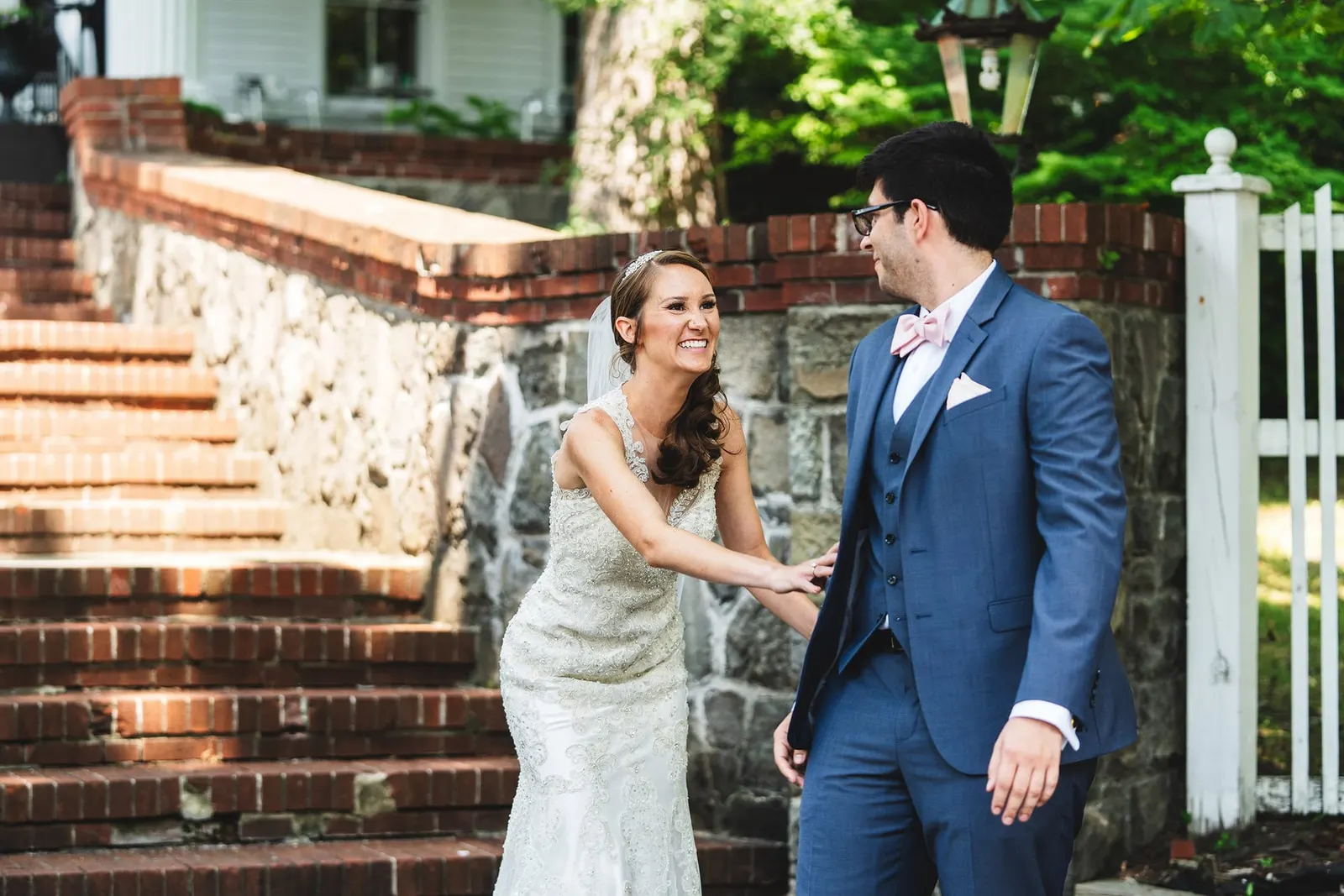 Bride tapping the groom's shoulder for their first look by the stone steps