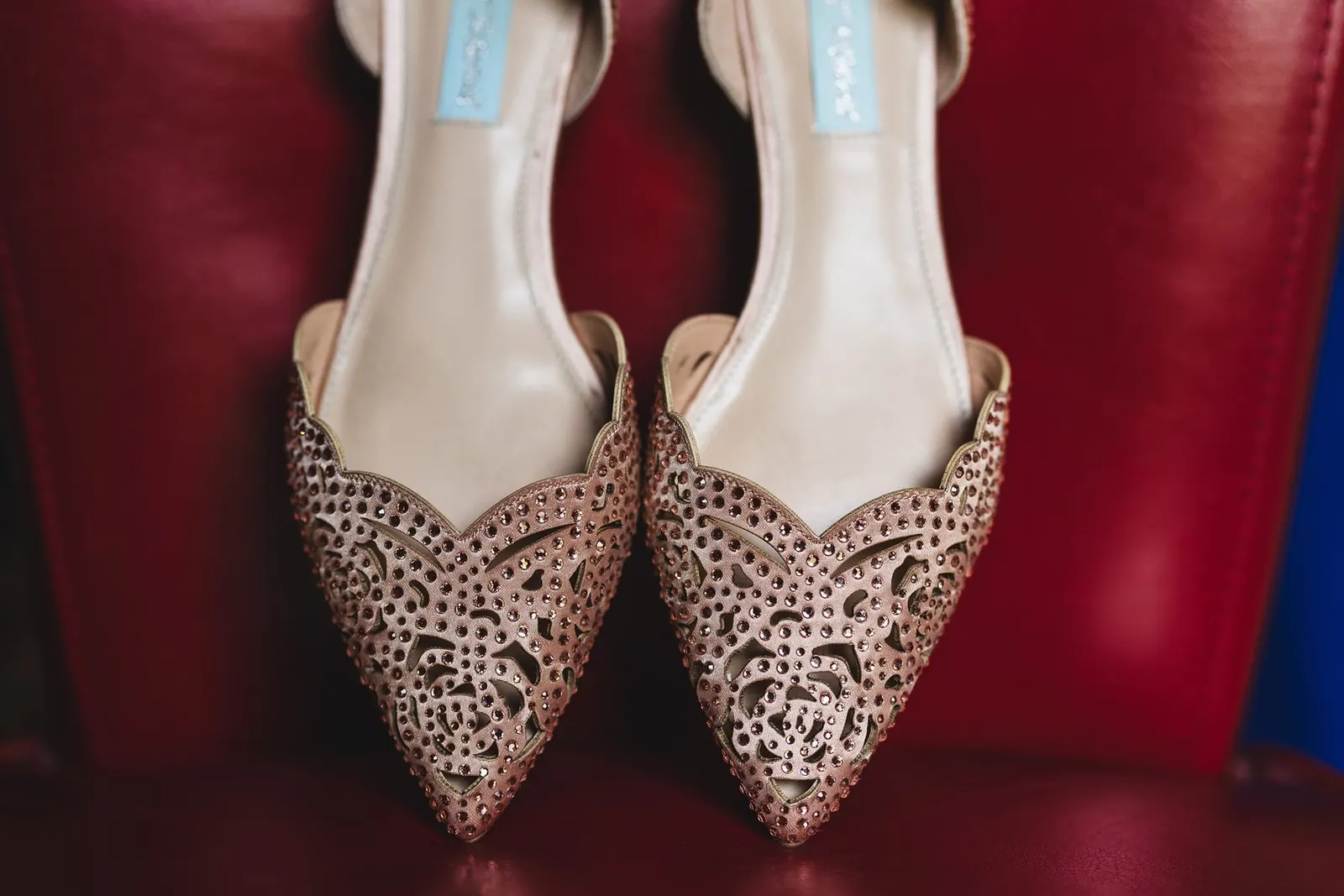 Blush embellished bridal heels on a red chair