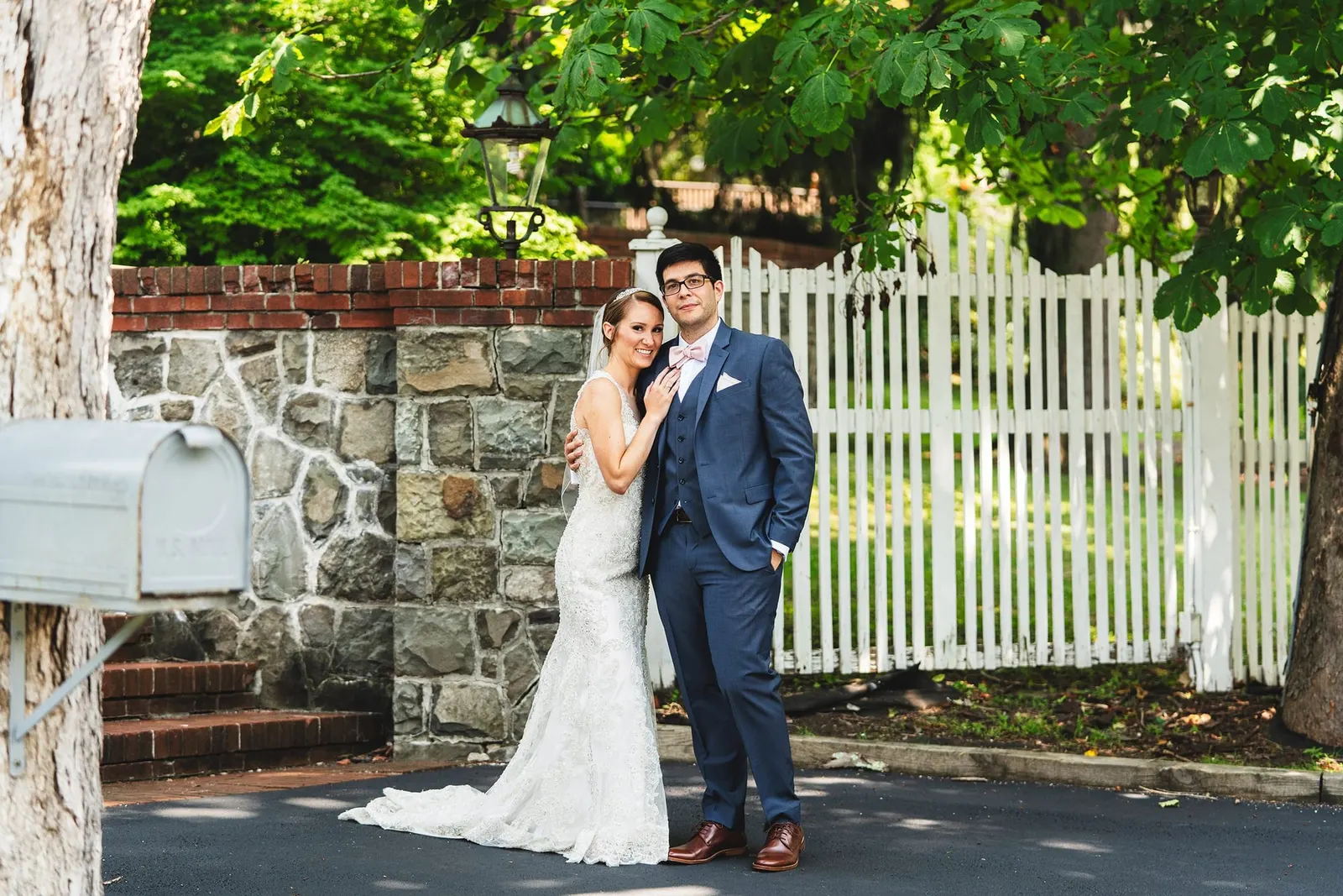 Bride and groom portrait beside a stone wall and mailbox