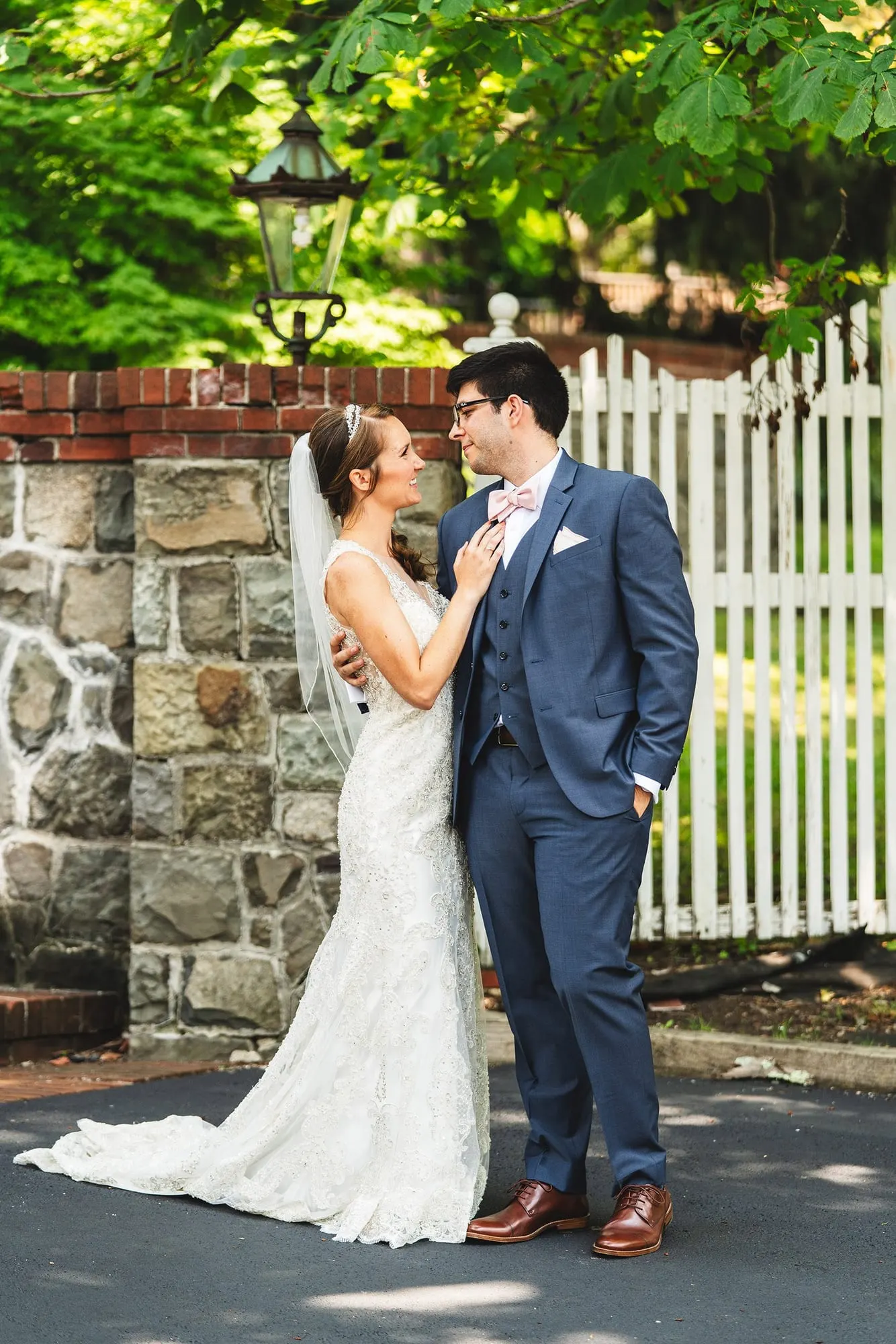 Bride and groom by the stone wall and white picket fence at Feast at Round Hill