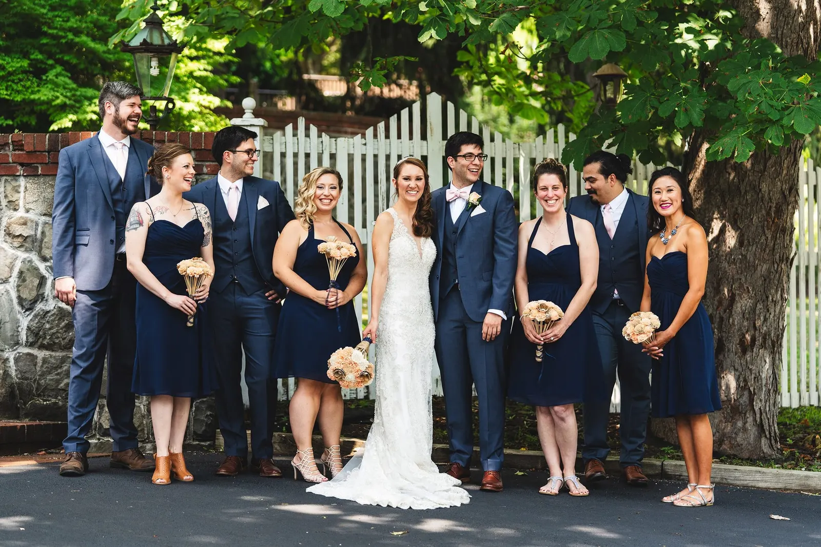 Wedding party in navy by the white picket fence
