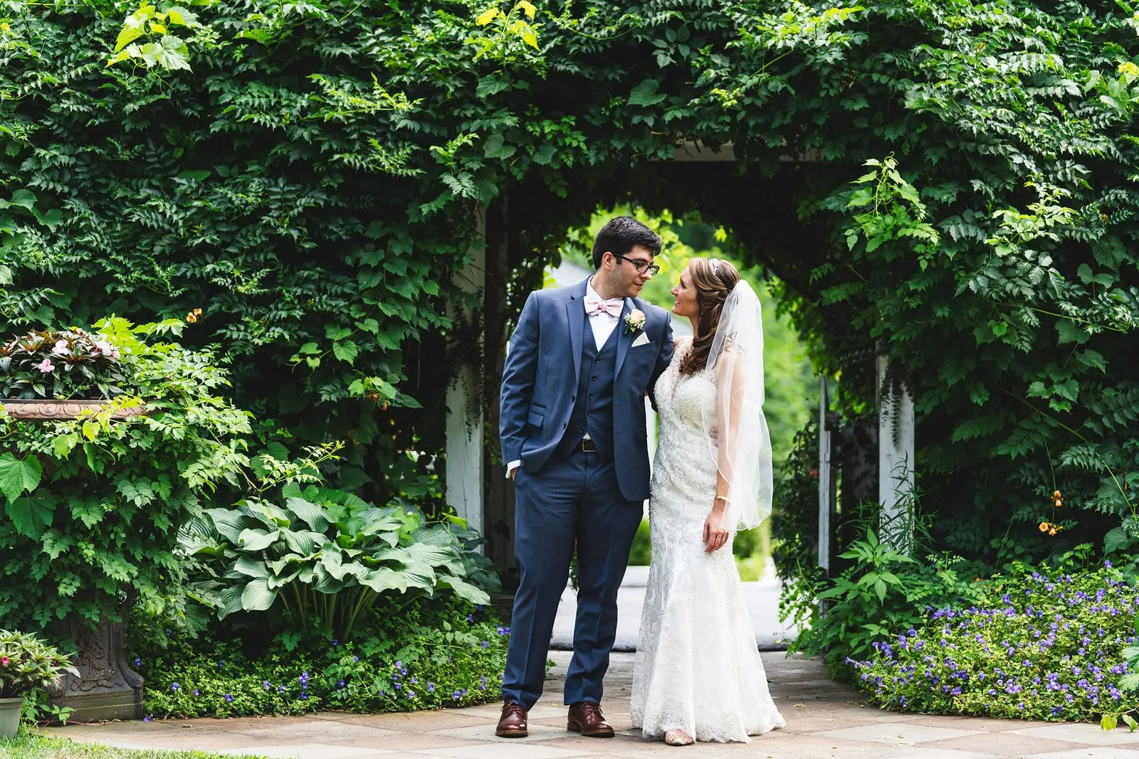 Bride and groom under an ivy-covered garden arch at Feast at Round Hill