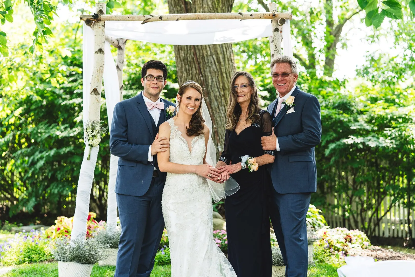 Bride and groom with family under the birch ceremony arbor