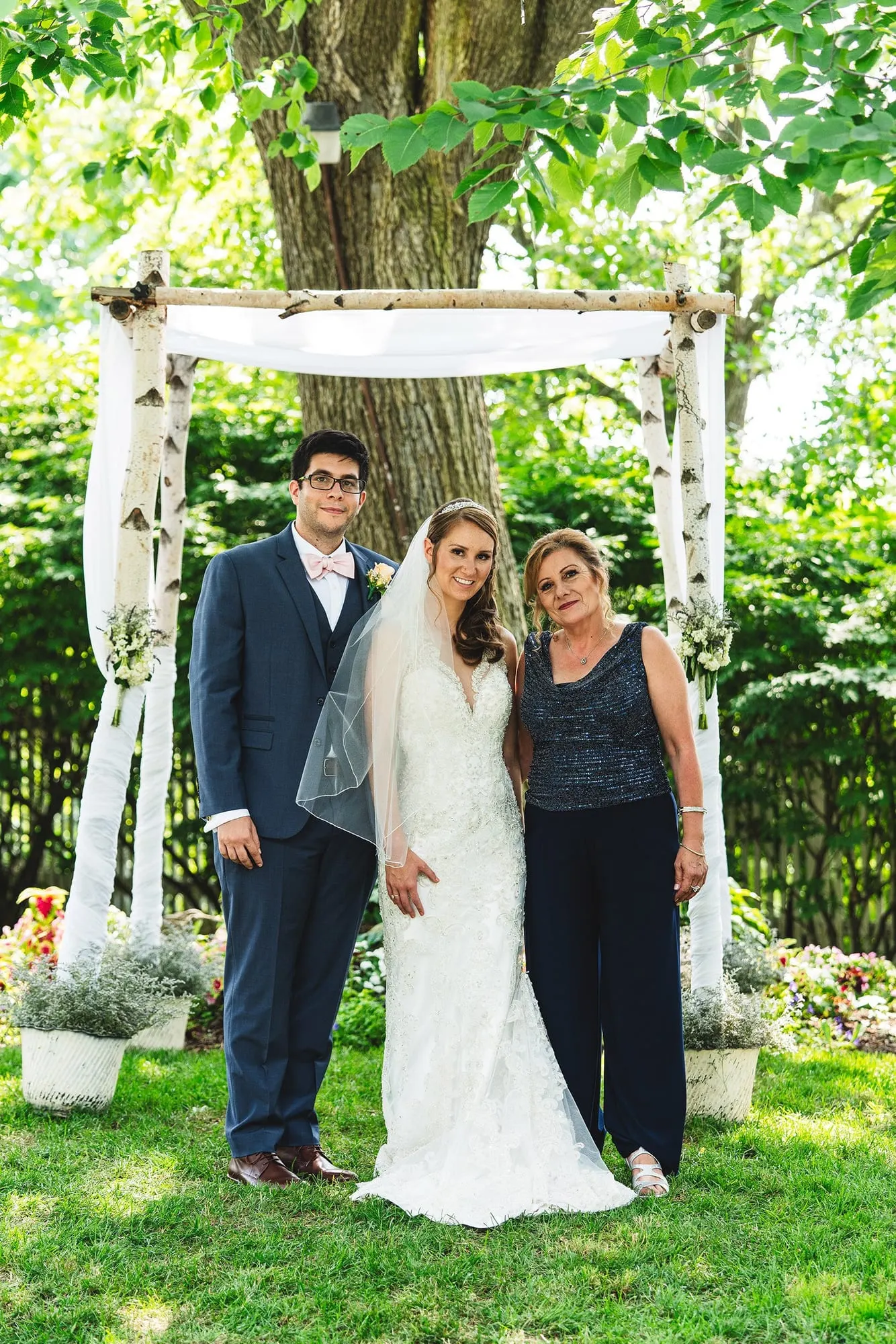 Bride and groom with a family member on the lawn