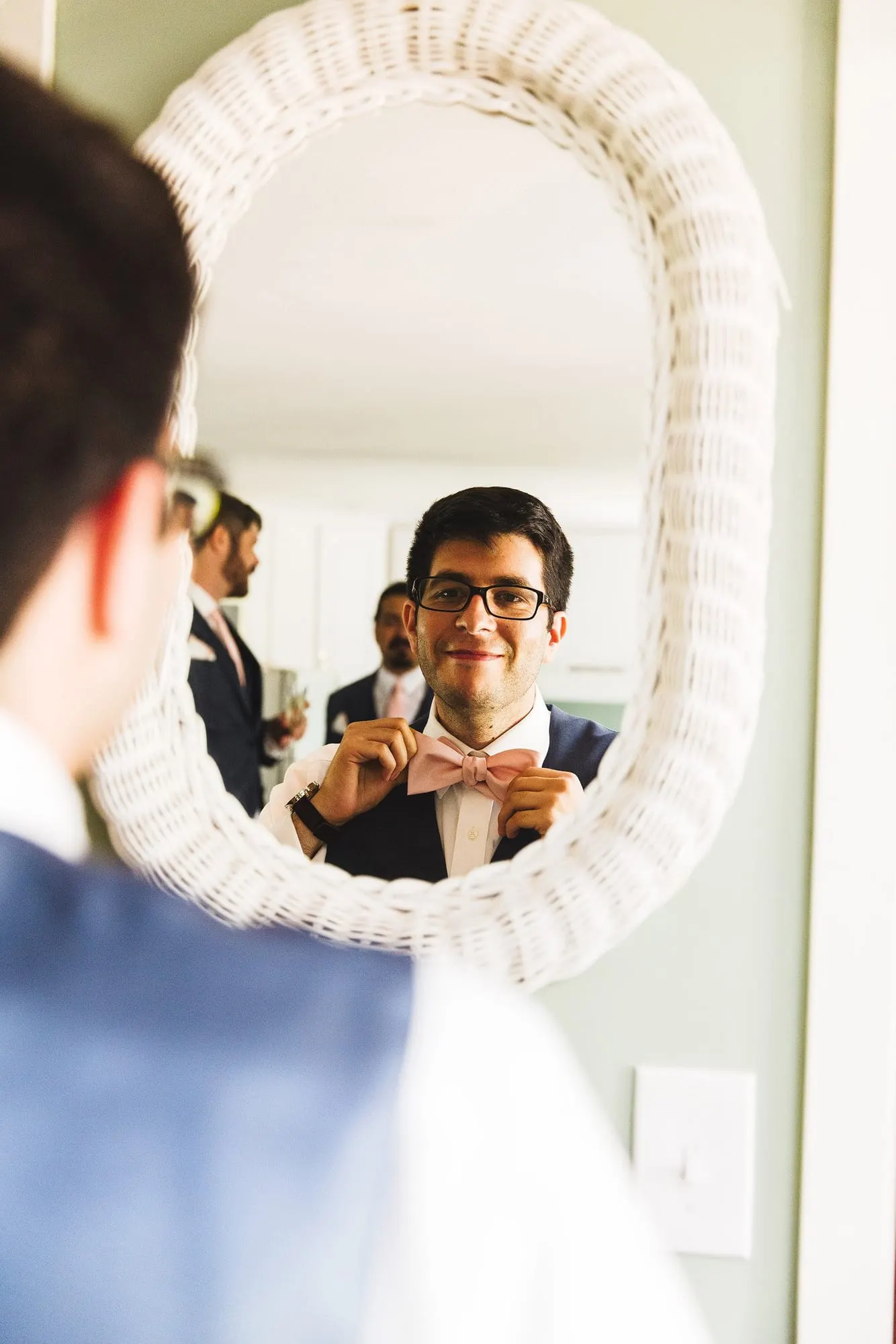 Groom reflected in an oval mirror while getting ready