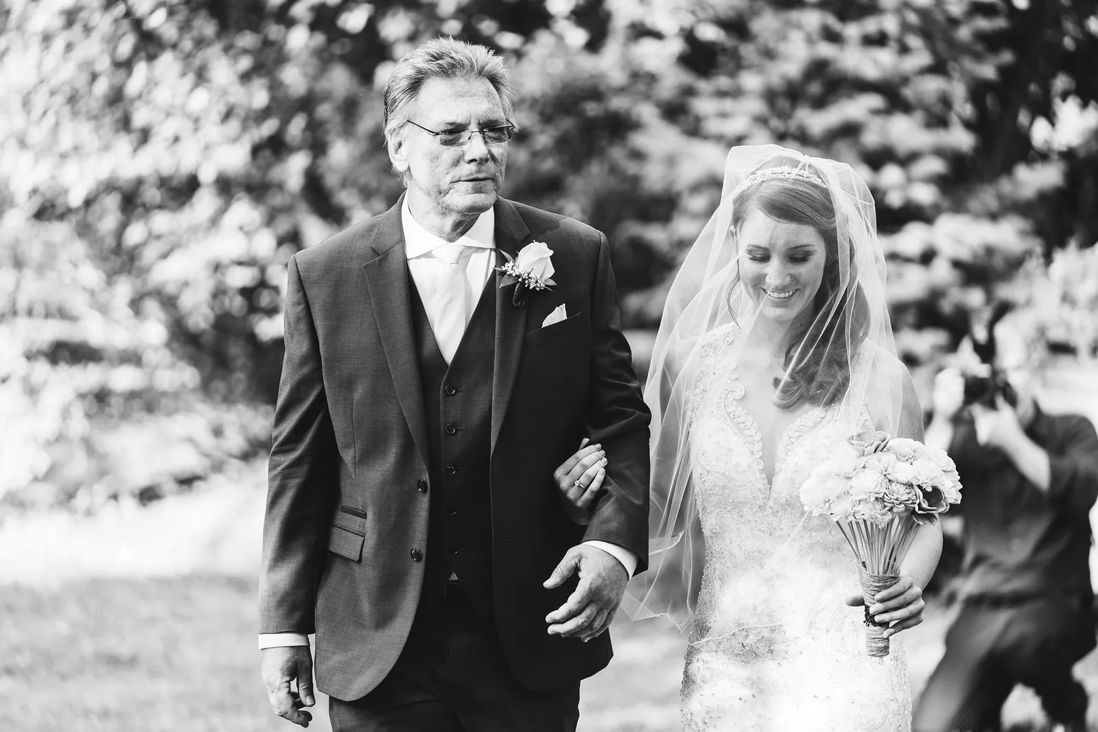 Black and white photo of the bride being escorted down the aisle