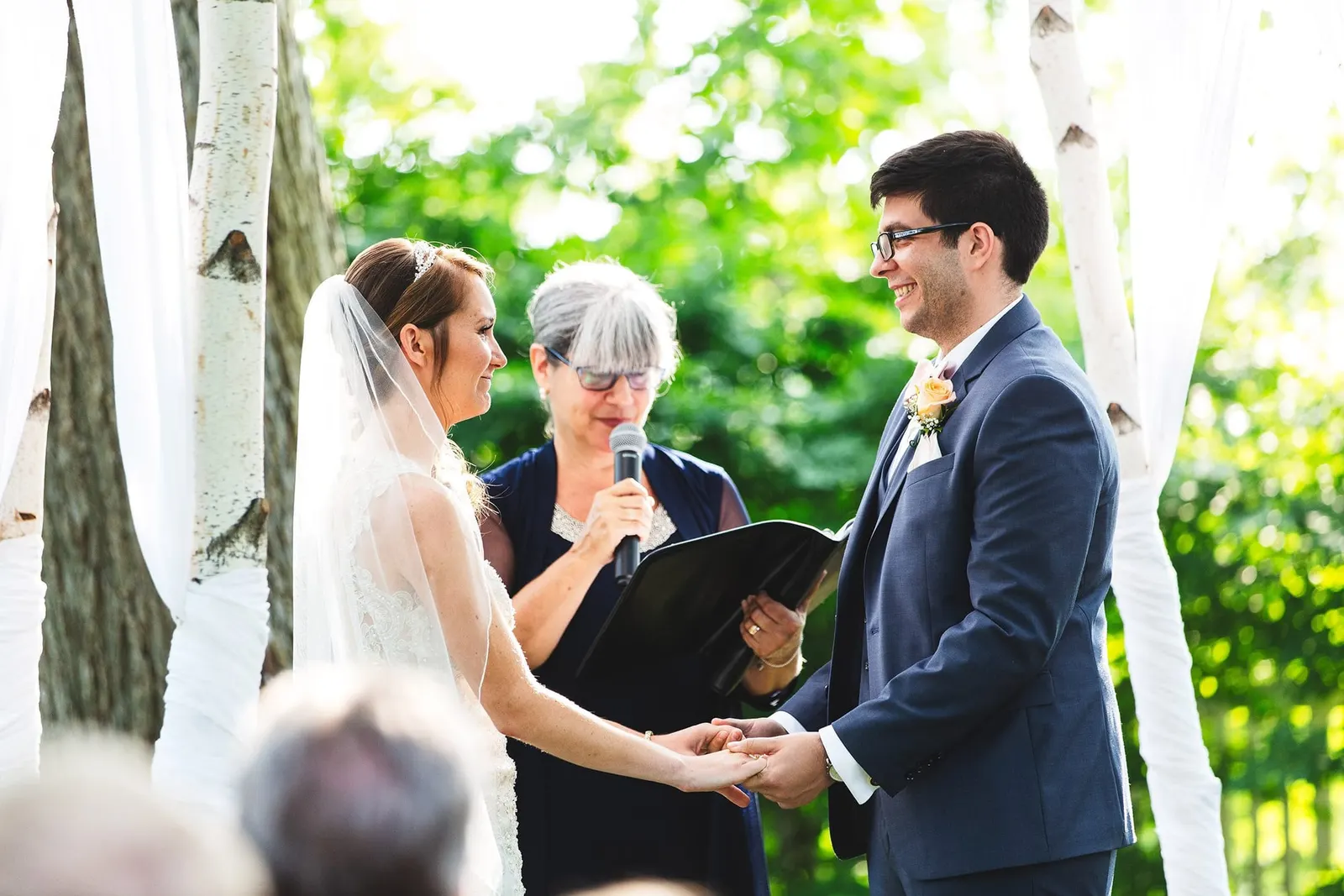 Bride and groom holding hands as the officiant reads