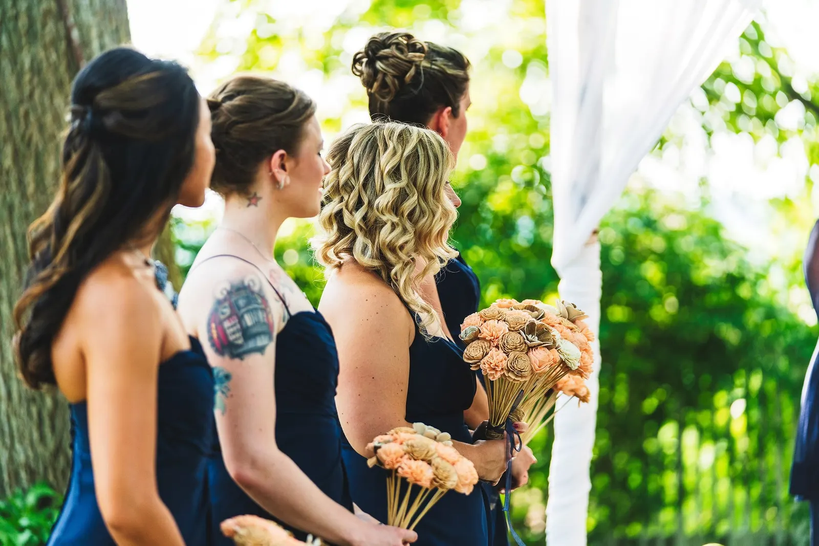 Bridesmaids holding peach bouquets during the ceremony