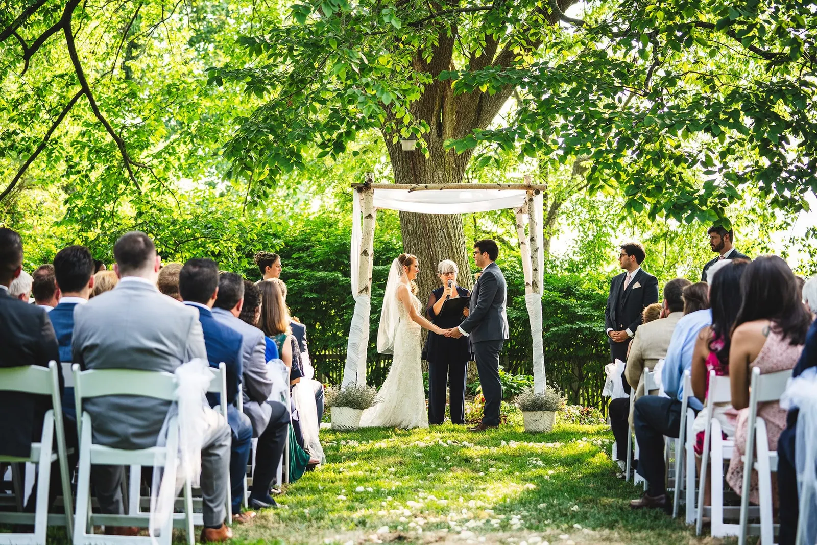 Ceremony under the birch arbor with guests seated on the lawn
