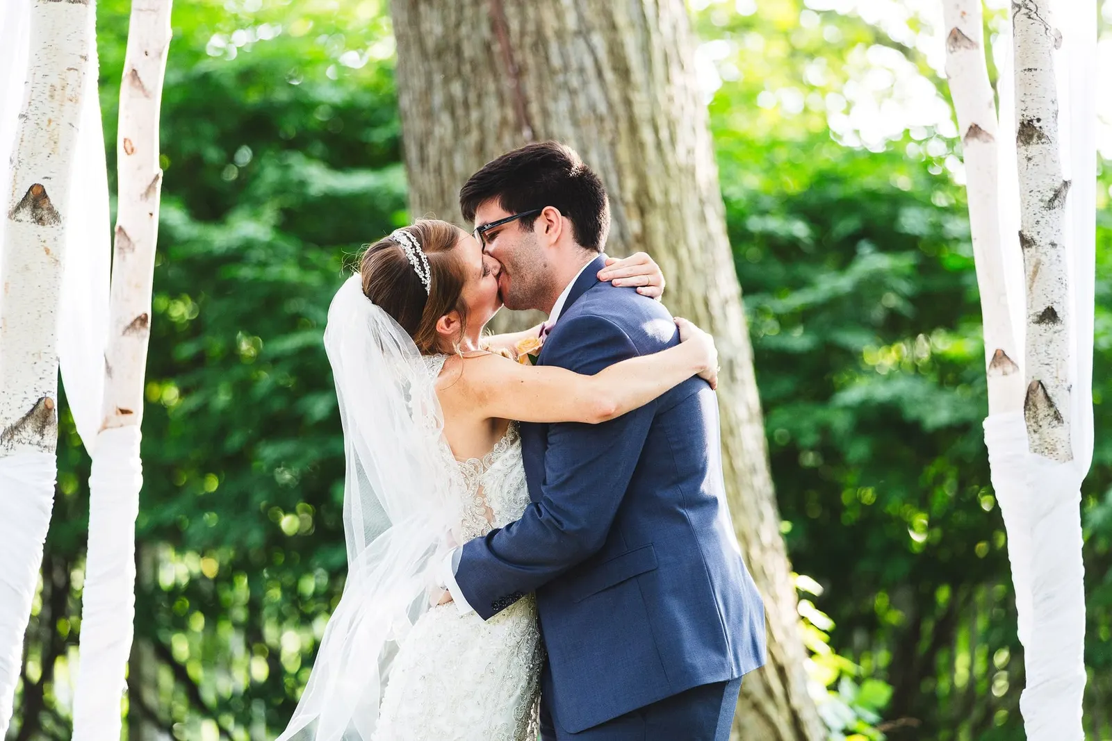 Bride and groom's first kiss under the birch arbor