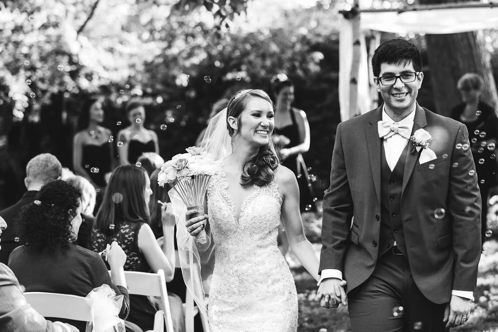 Black and white photo of the newlyweds laughing during their recessional