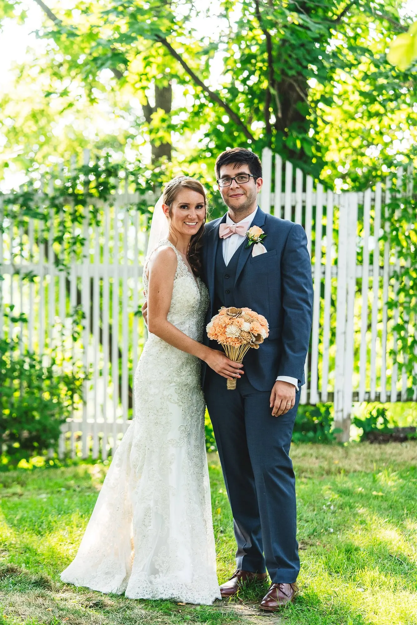 Newlyweds by the white picket fence after the ceremony