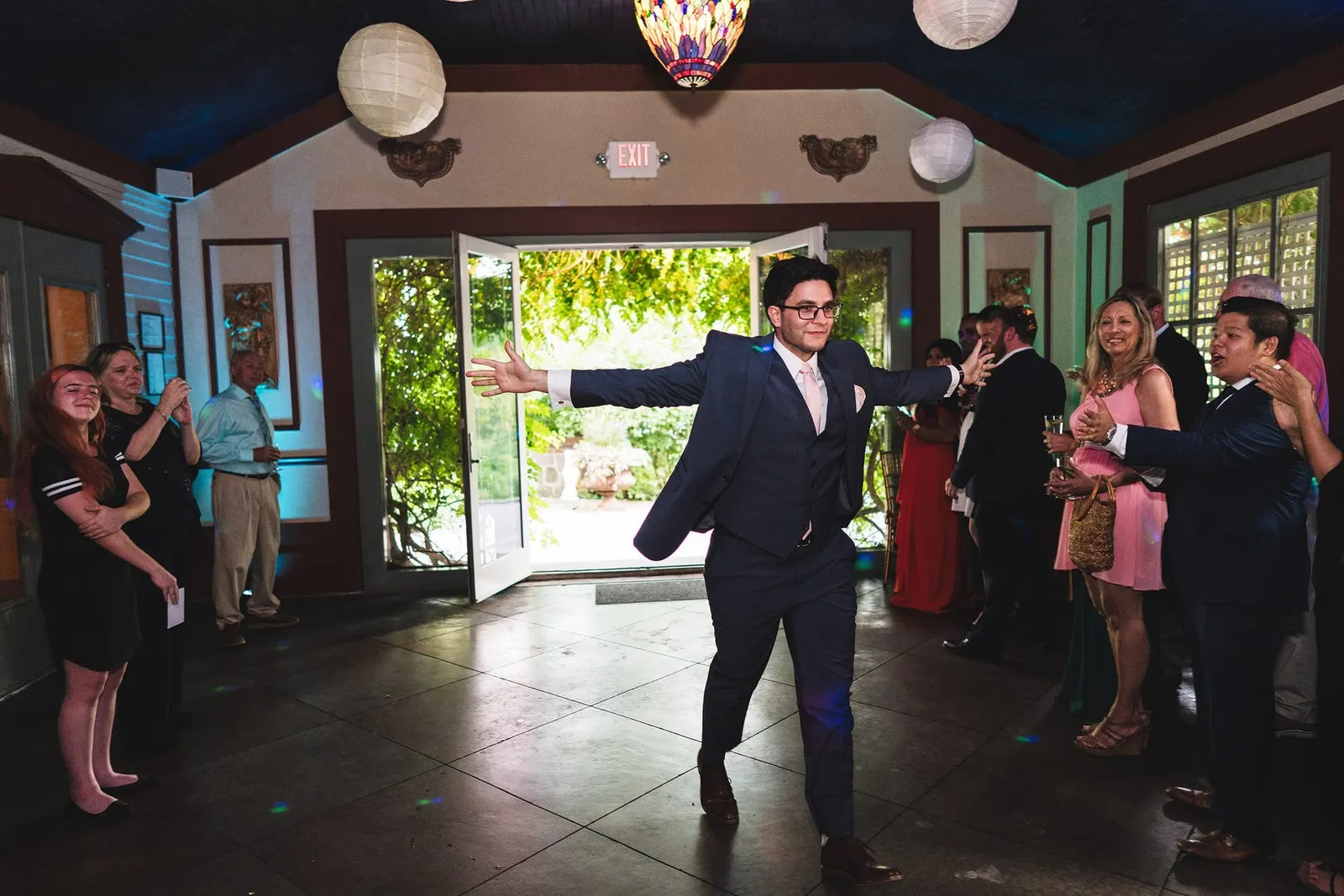 Groom dancing into the reception under paper lanterns