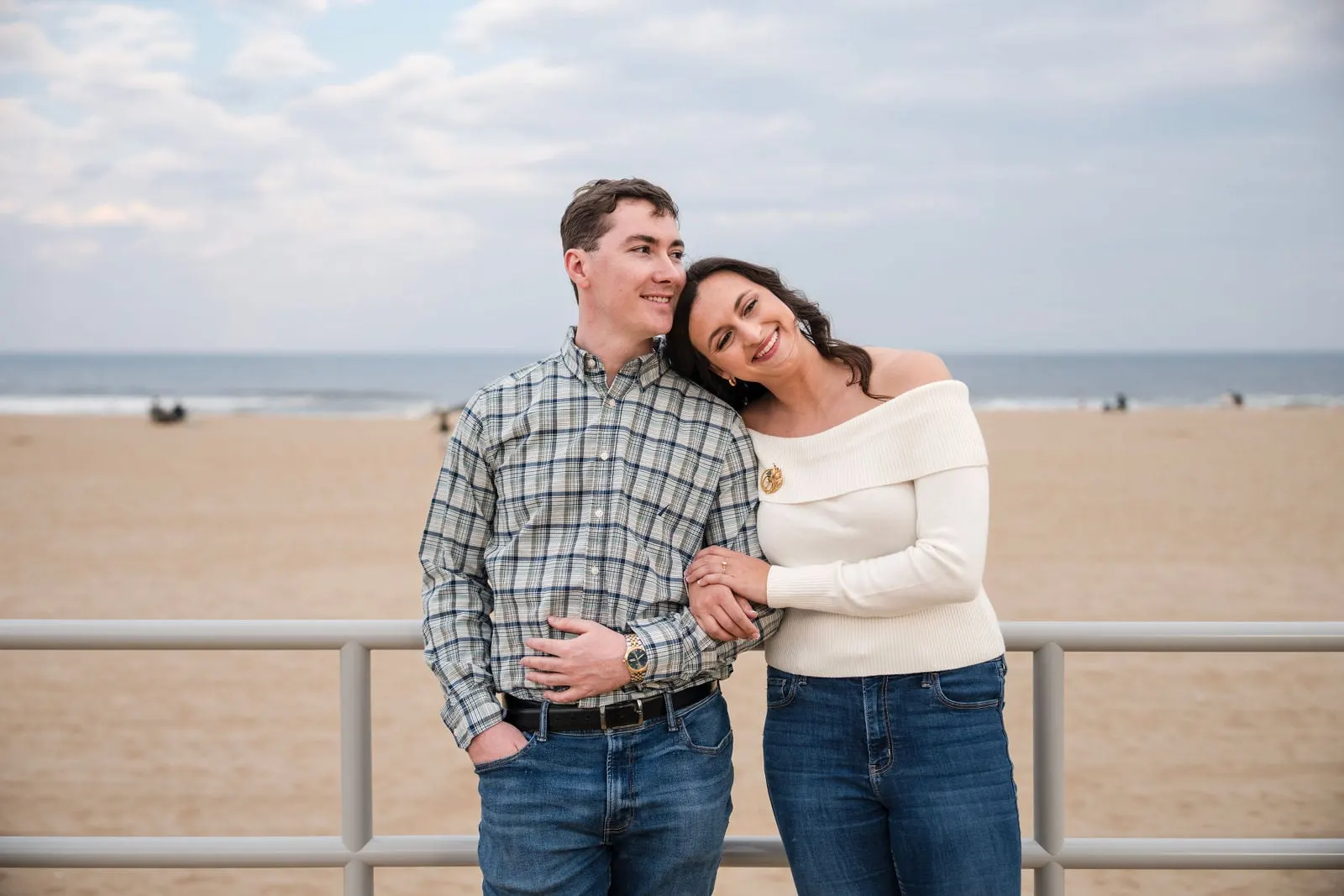 Bride-to-be resting her head on her fiancé's shoulder at the Asbury Park boardwalk