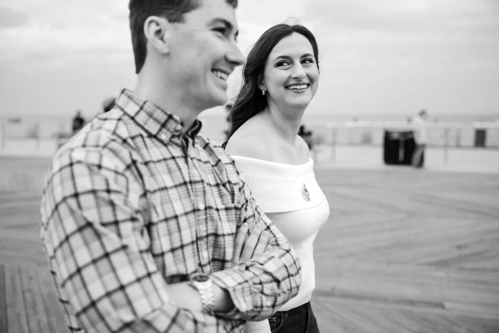 Black and white photo of the engaged couple smiling on the boardwalk