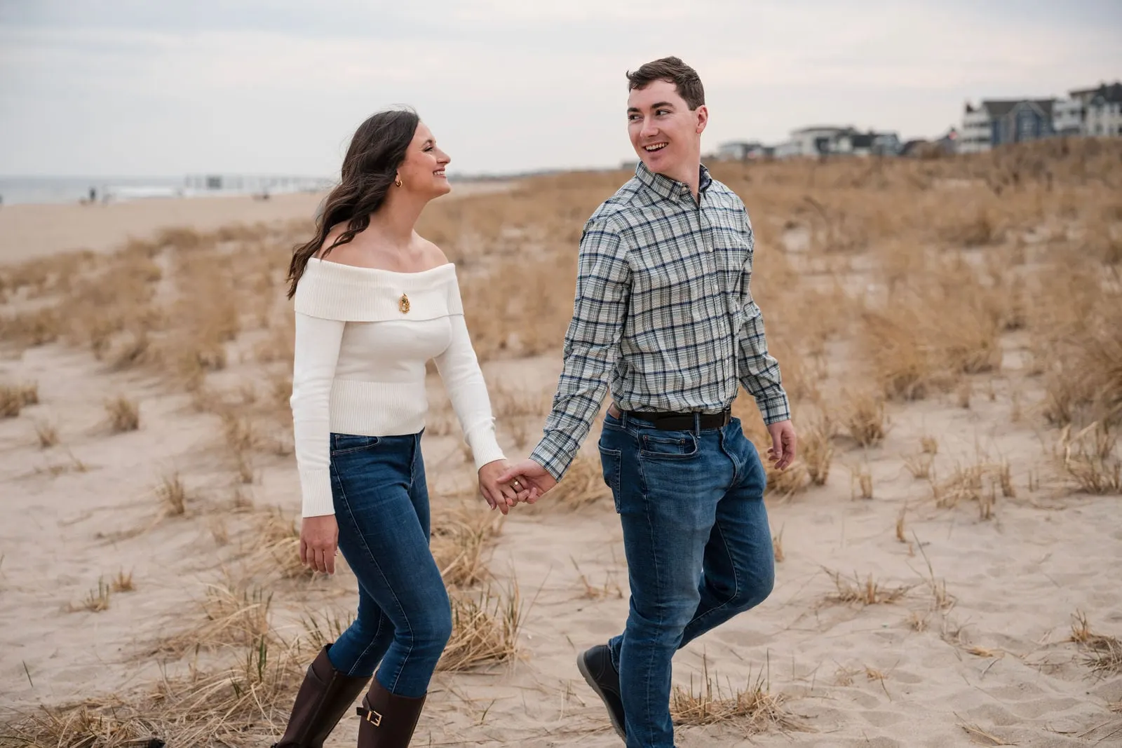 Couple walking hand in hand through golden dune grass