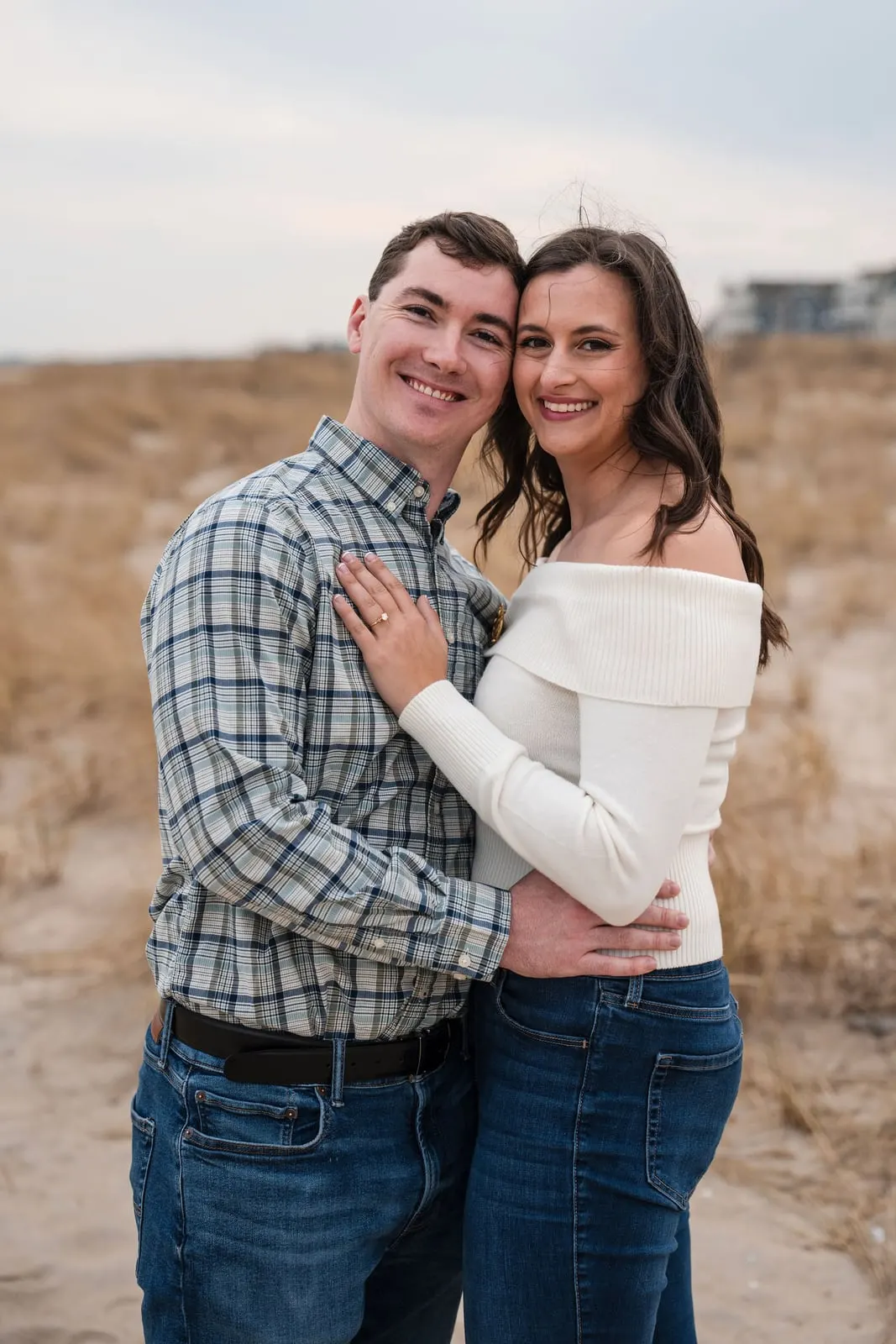 Engaged couple cheek to cheek in the dunes