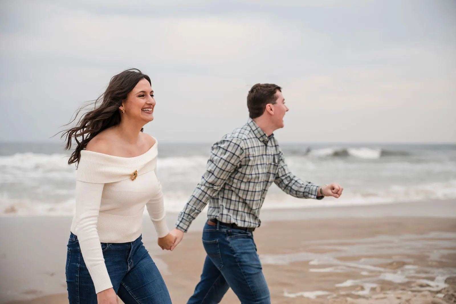 Couple running hand in hand along the water's edge
