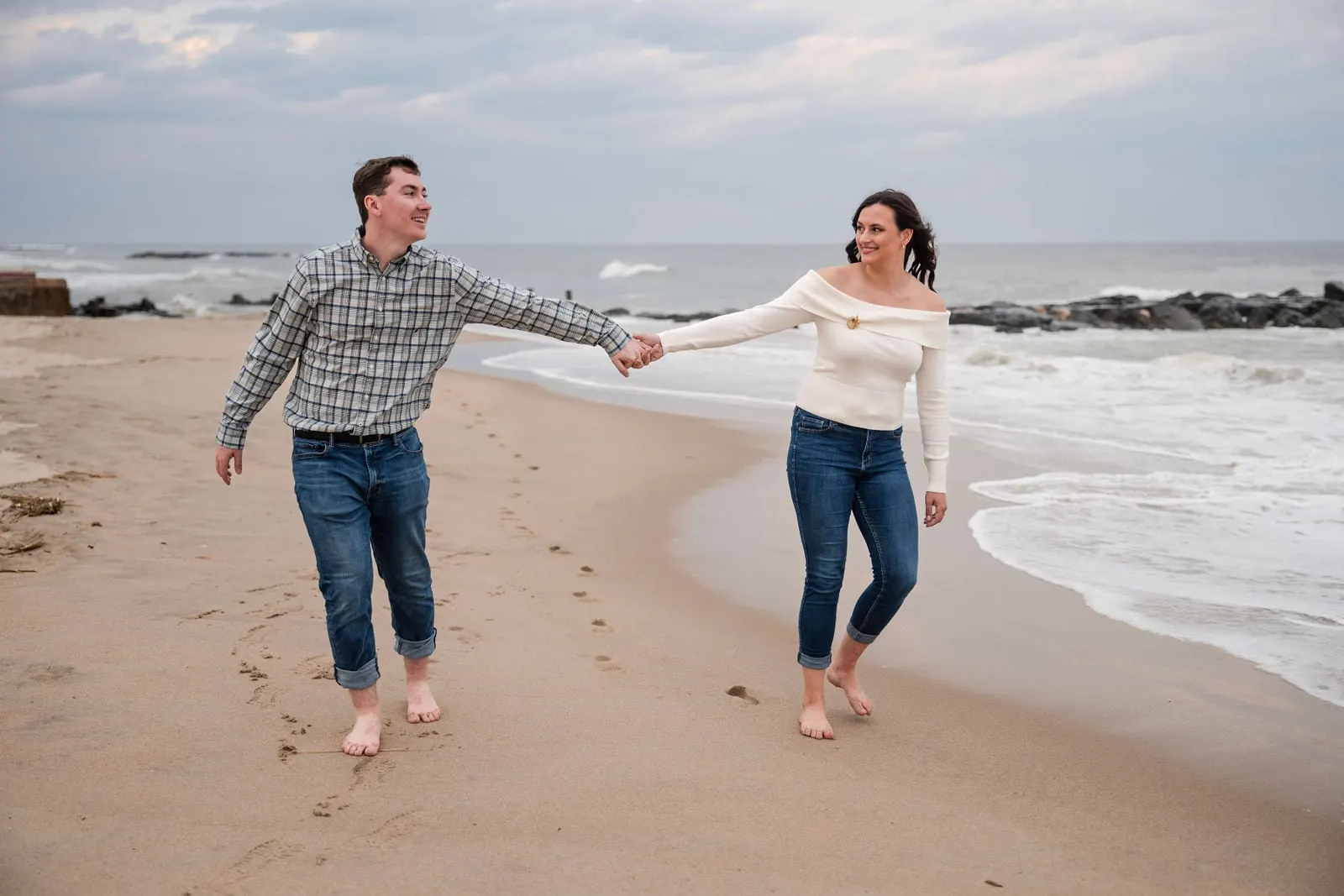 Couple swinging hands as they run barefoot along the beach
