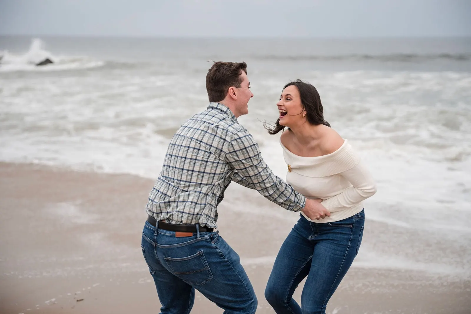Couple laughing and spinning by the waves in Asbury Park