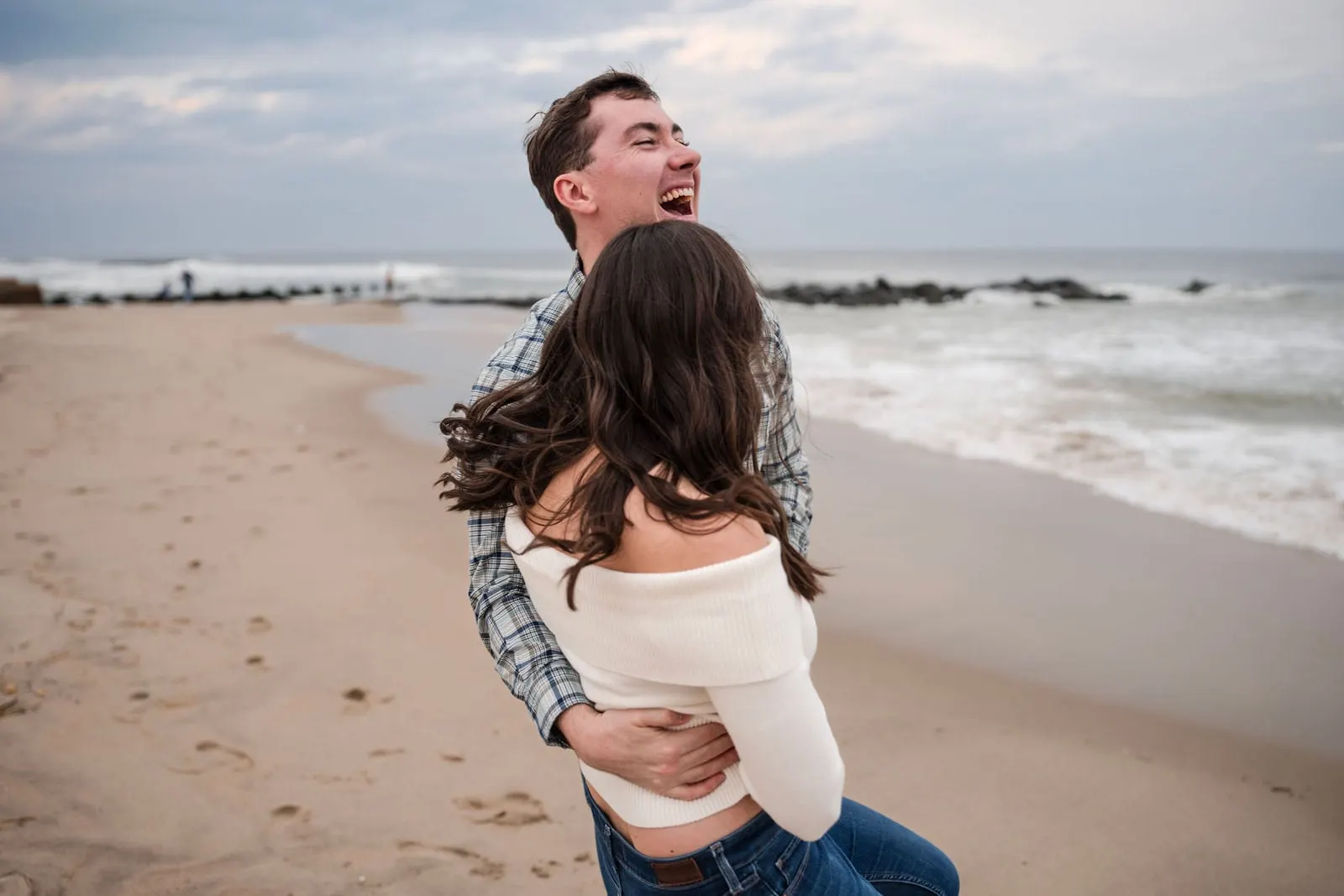 Fiancé lifting his partner off her feet on the beach
