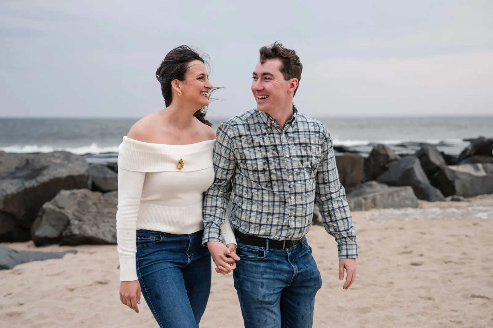 Couple walking together on the sand beside the rocks