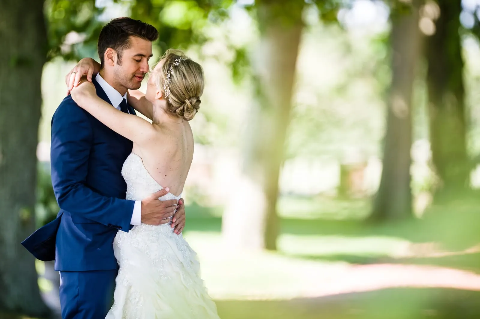 Bride and groom embracing under the trees during their first look