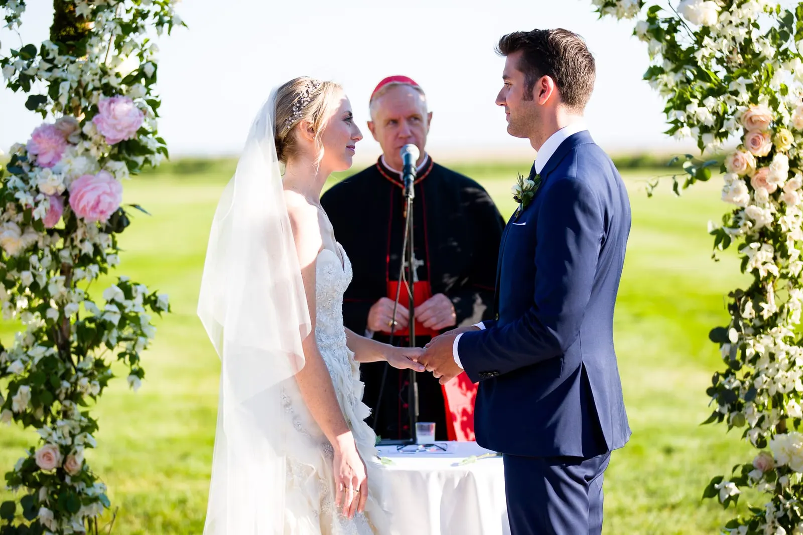 Bride and groom exchanging vows under the floral arch