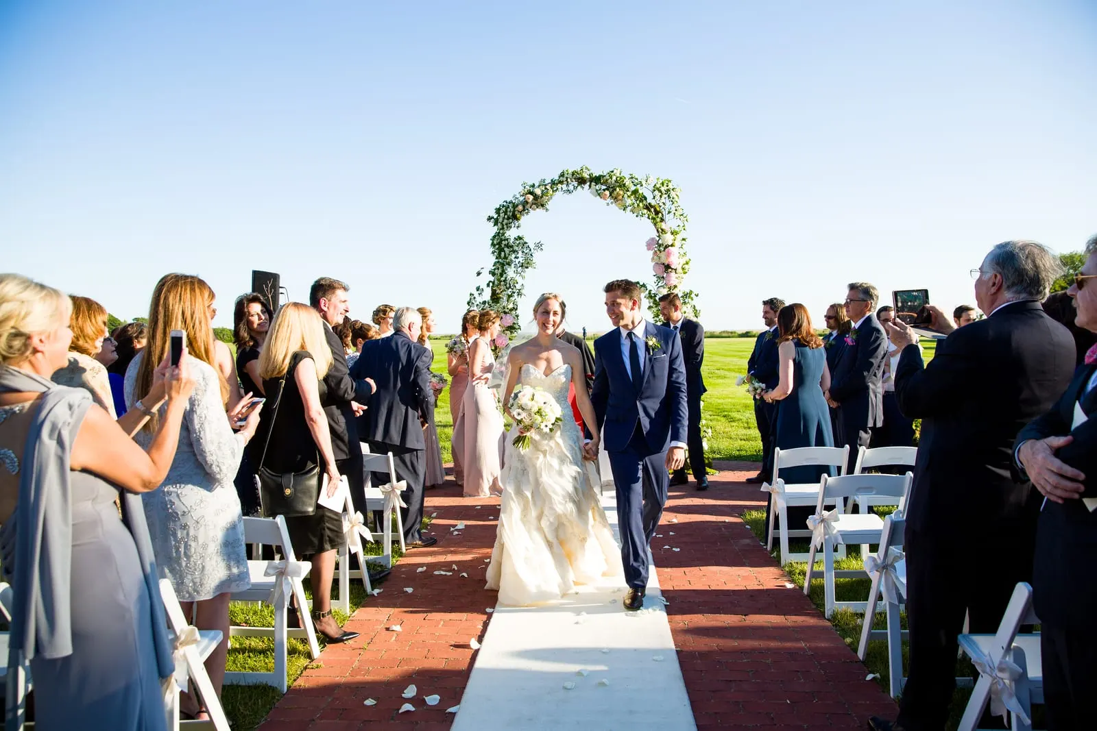Newlyweds walking back down the aisle as guests celebrate