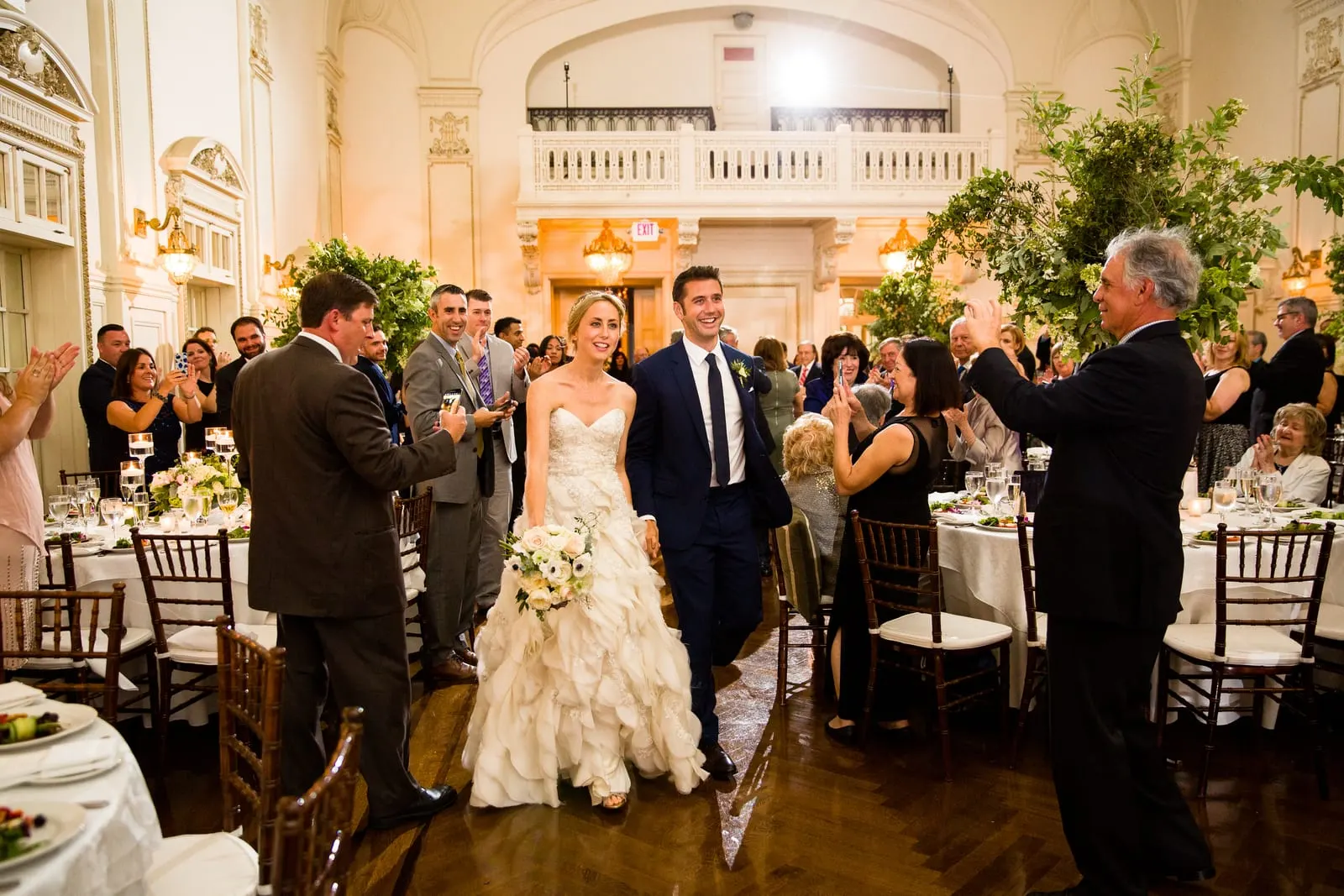 Guests cheering as the bride and groom make their entrance into the ballroom