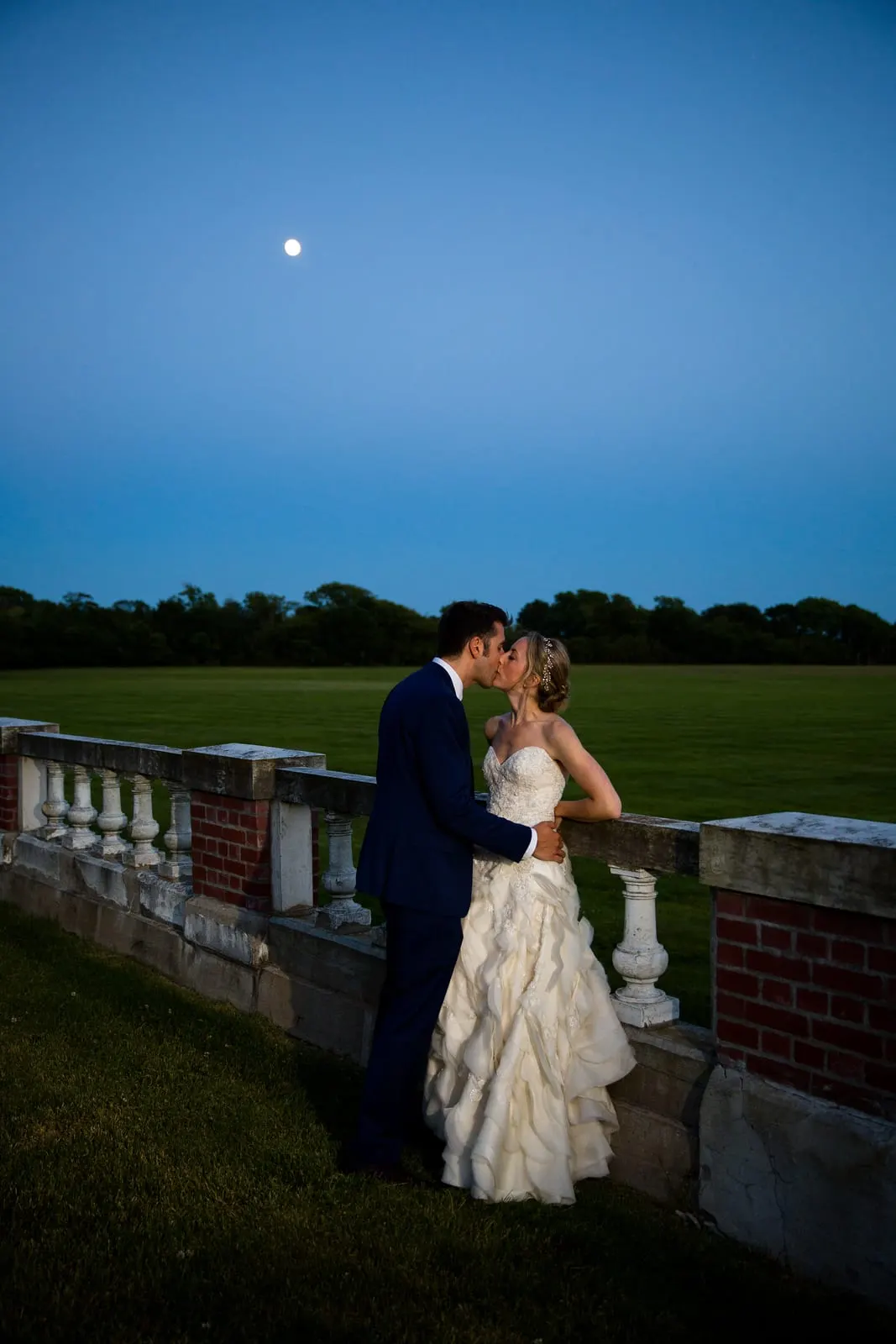 Bride and groom kissing under a deep blue night sky