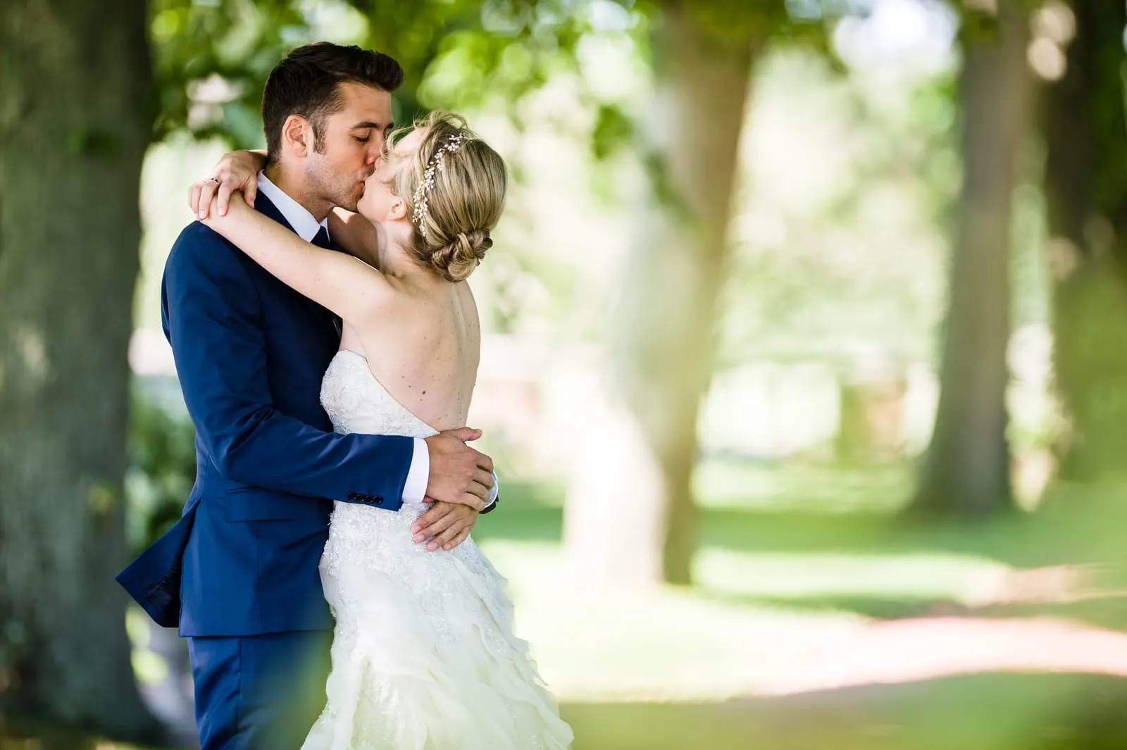 Groom kissing the bride under the trees