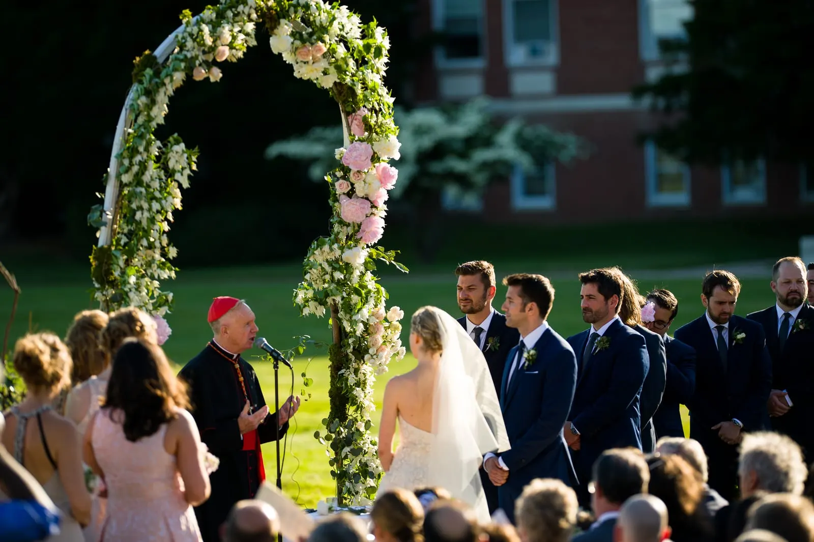Ceremony under the floral arch surrounded by guests