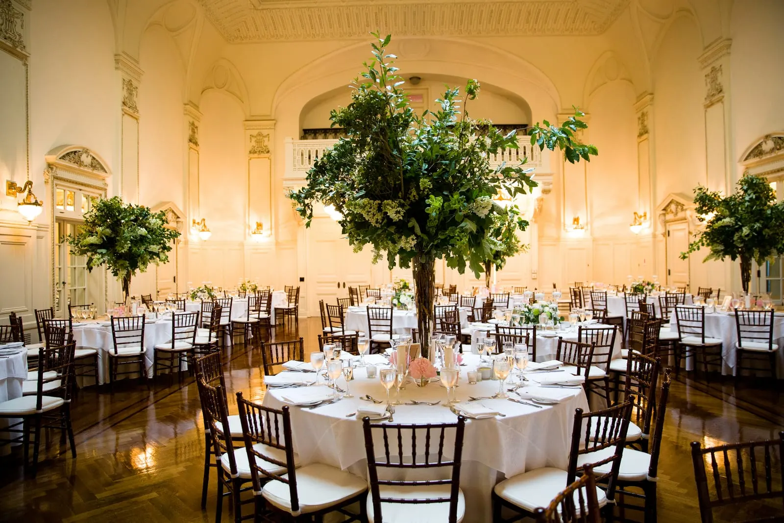 Tall greenery centerpieces over candlelit tables