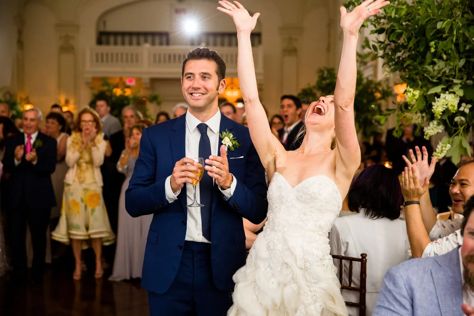 Bride throwing her arms up on a packed dance floor