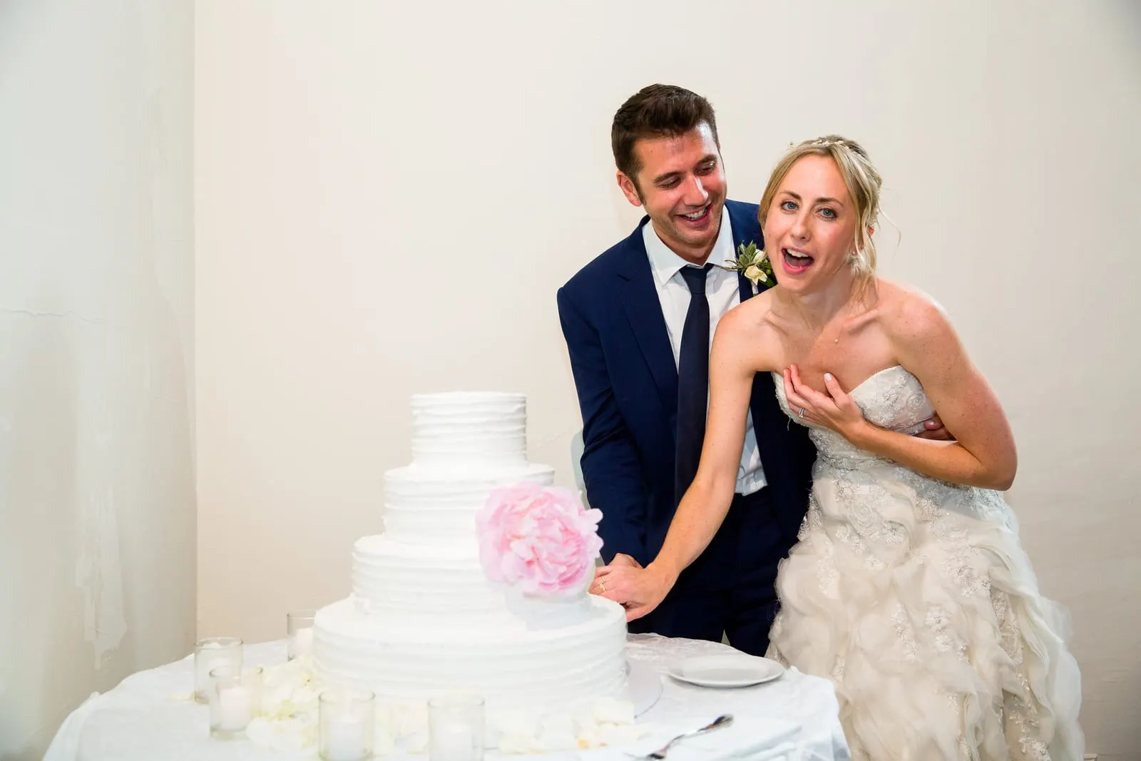 Bride and groom laughing as they cut the cake