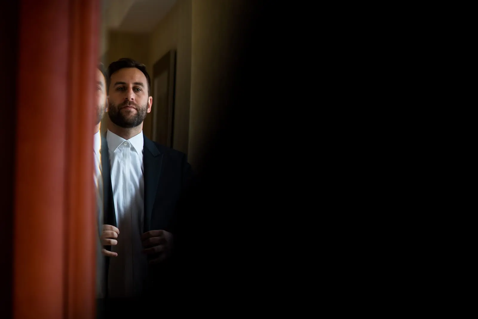 Groom framed in a doorway as he gets dressed
