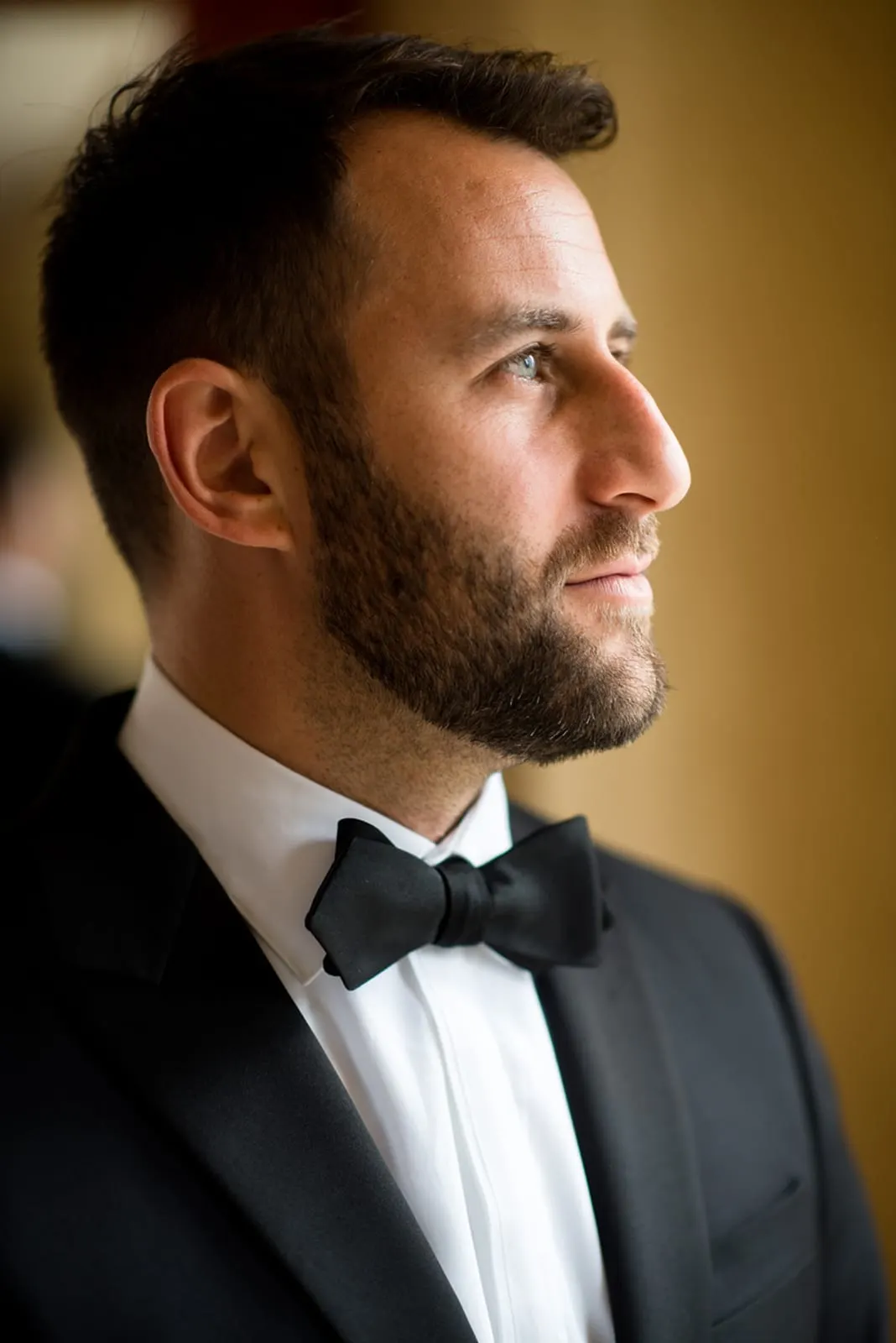 Groom in his tuxedo by the window in soft side light