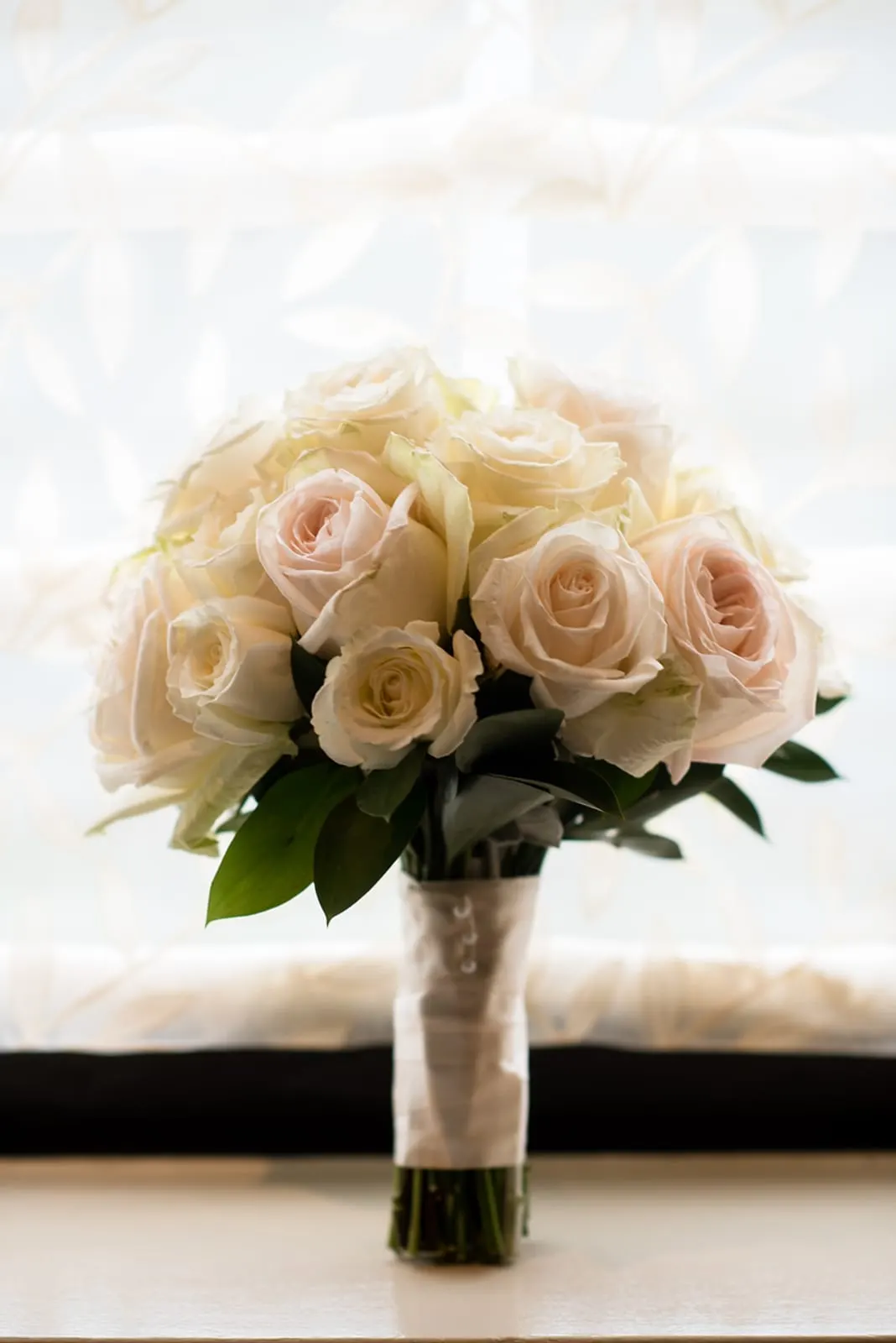 Bouquet of blush and ivory roses in the window
