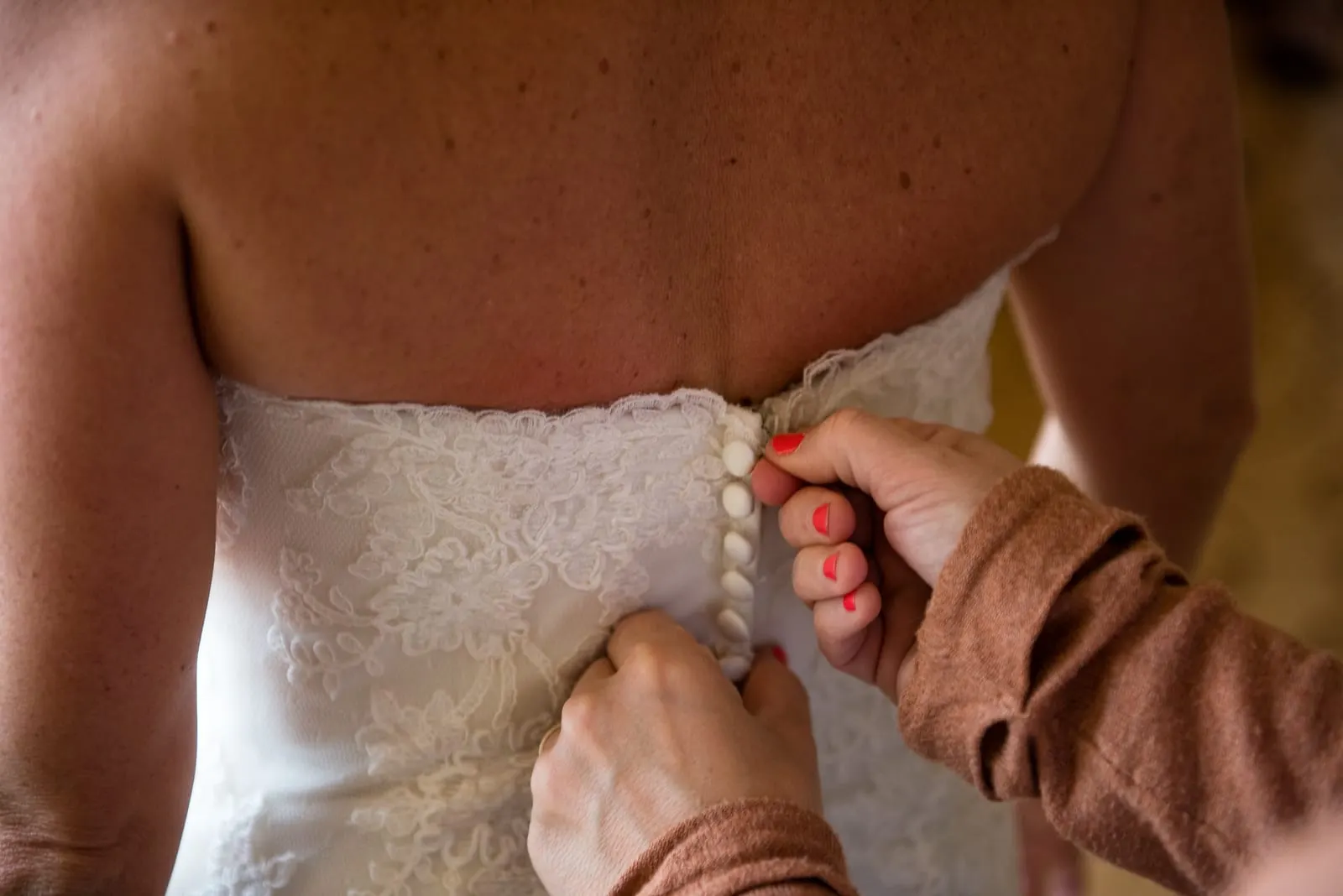 Buttoning the lace back of the wedding gown
