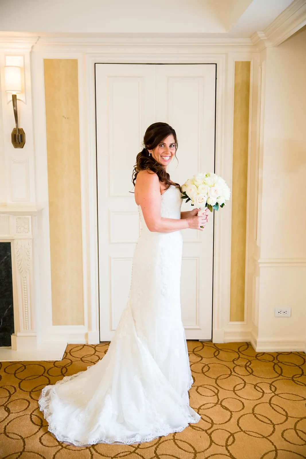Bride in her lace gown holding her bouquet in the Essex House suite
