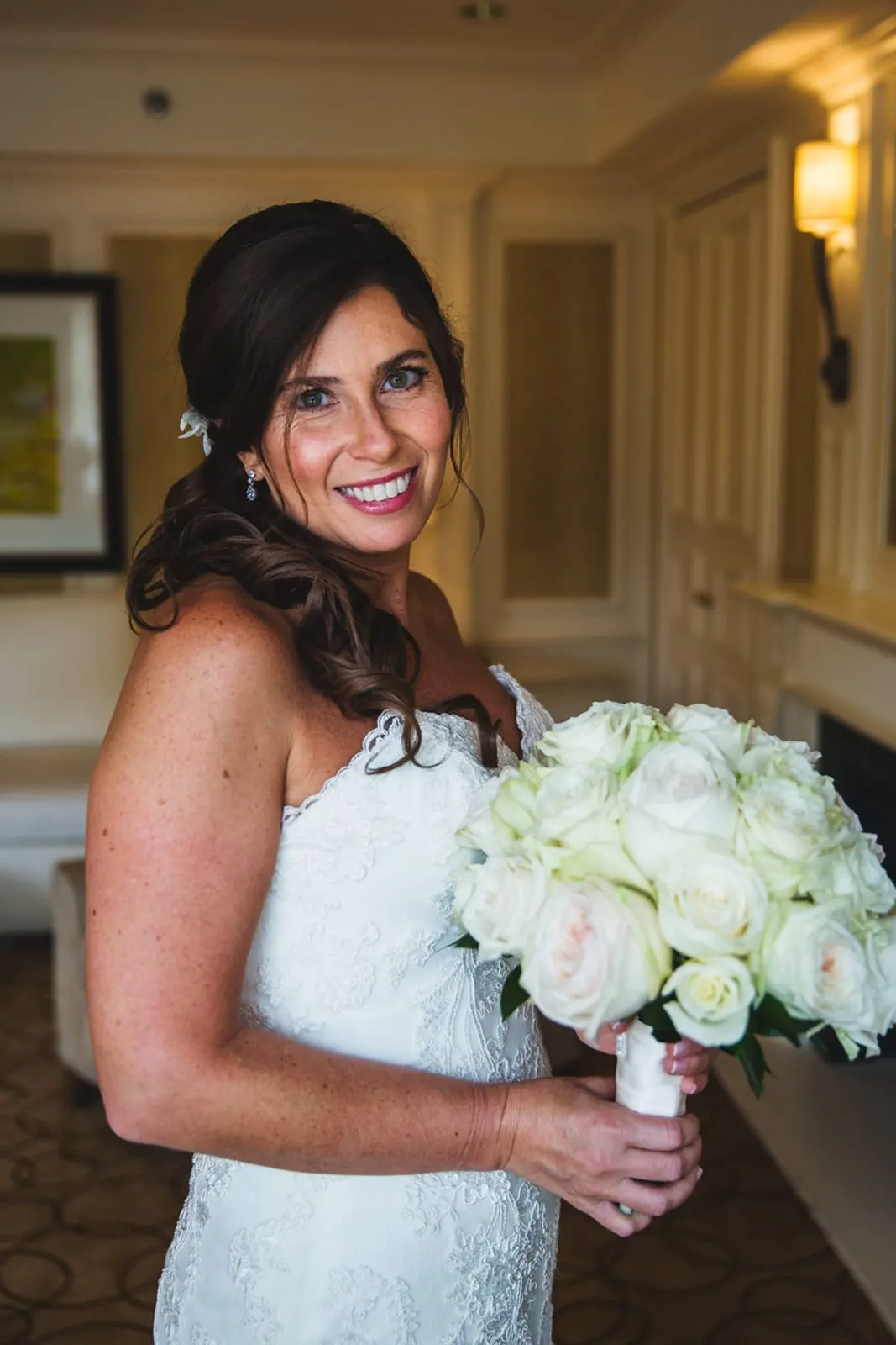Bride smiling over her shoulder with her bouquet of white roses