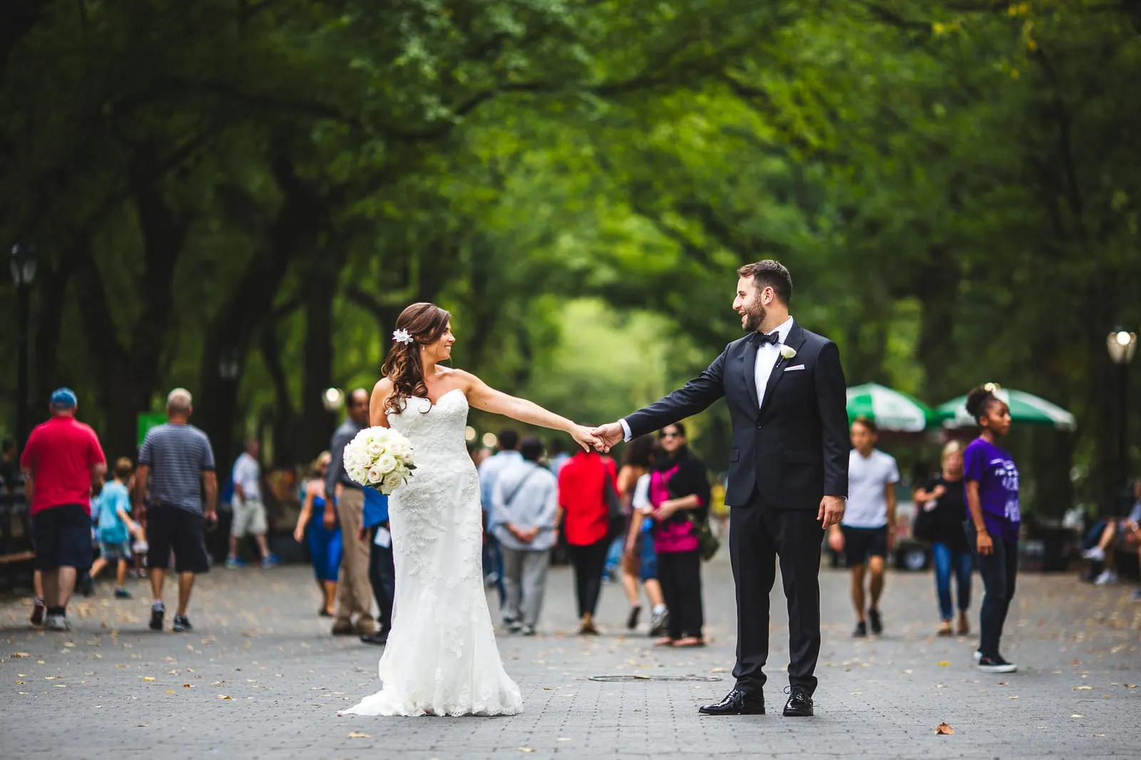 Bride and groom reaching for each other on the Mall in Central Park